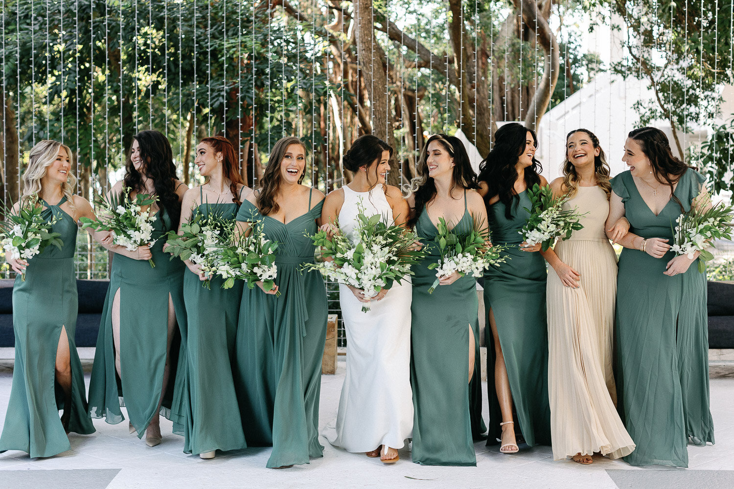 Bridesmaids walking together with bride wearing sage green dresses