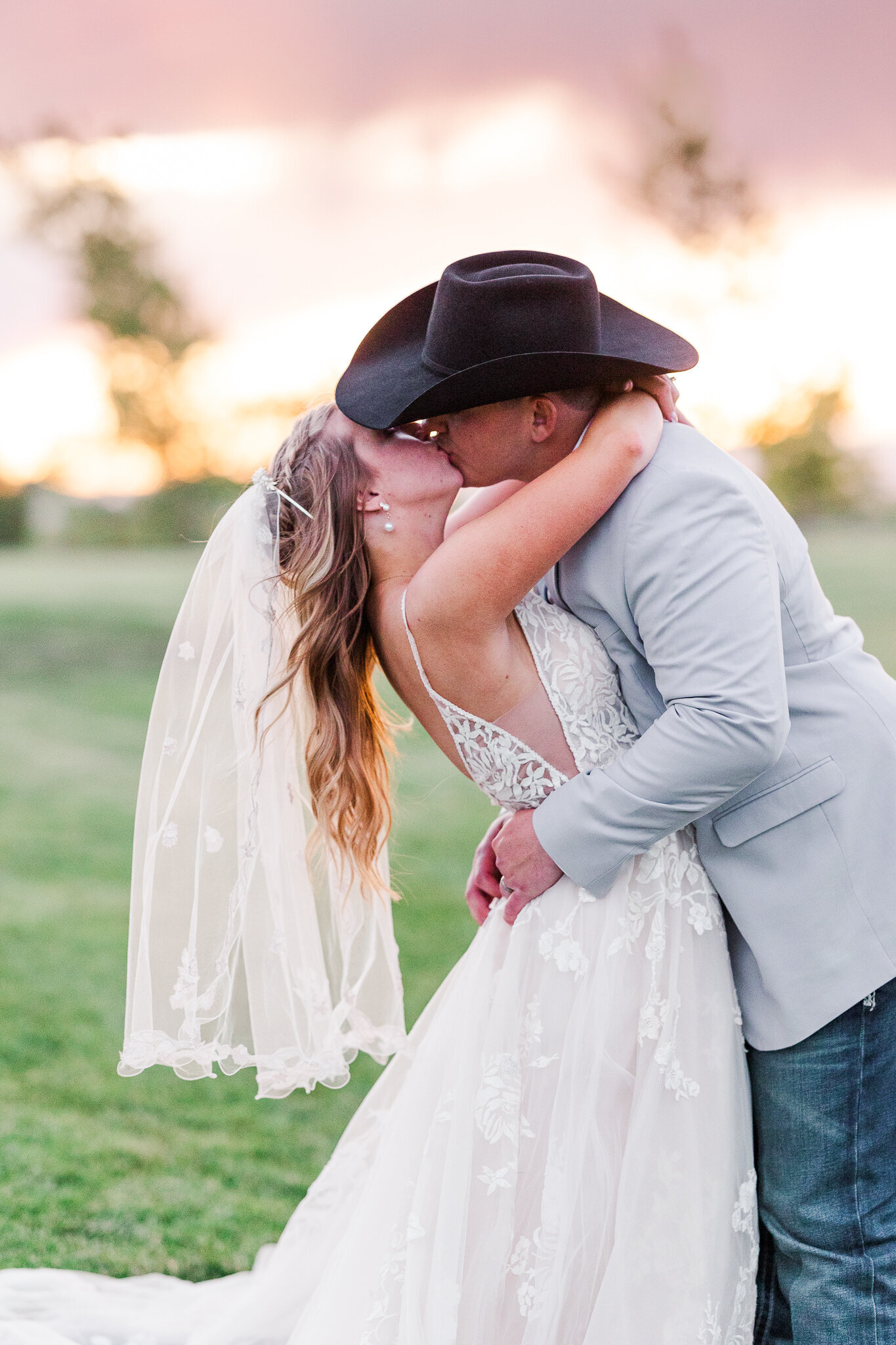 Bride and groom sharing a romantic kiss with glowing sunset light behind them at Absolute Prestige in Loma, Colorado