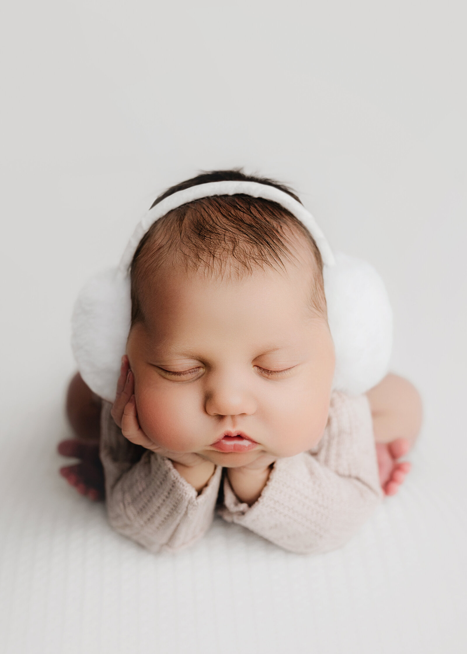 Newborn baby girl wearing earmuffs in oswego, new york portrait studio