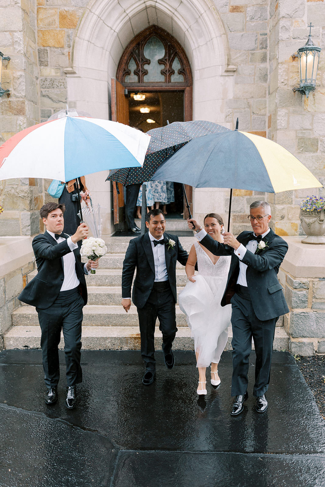 Rainy wedding day exit wityh umbrellas