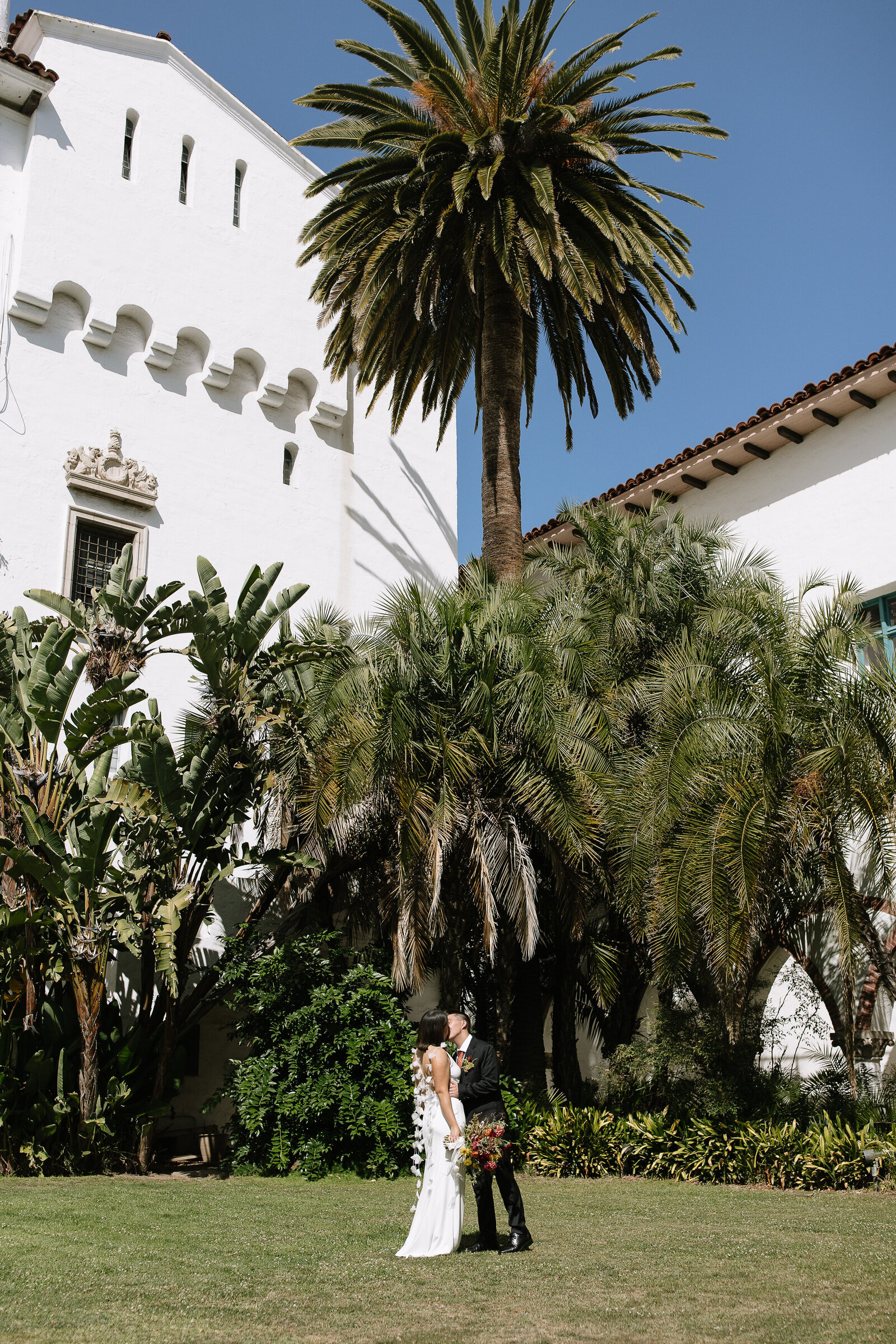 Bride and groom kiss under palm tree by best Northern California wedding photographers, Erica Rochelle Photography
