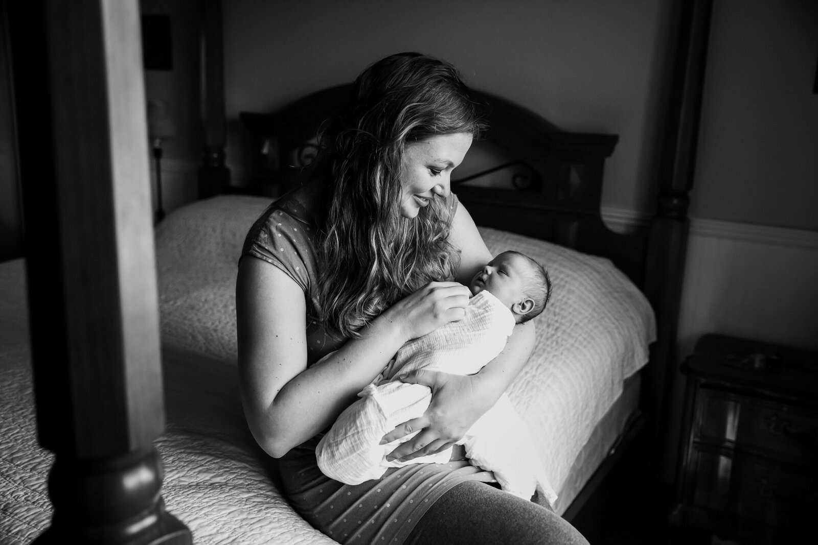 mom holding and admiring newborn baby in lifestyle newborn photography session