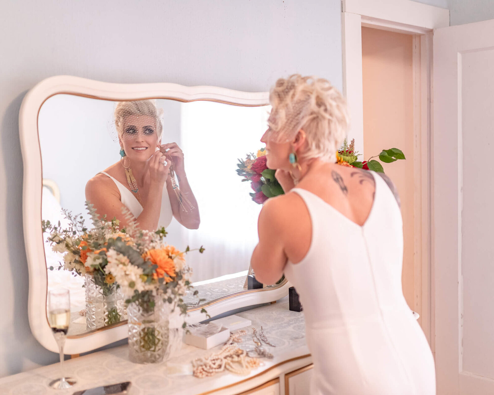 bride looking in mirror, putting on her earrings
