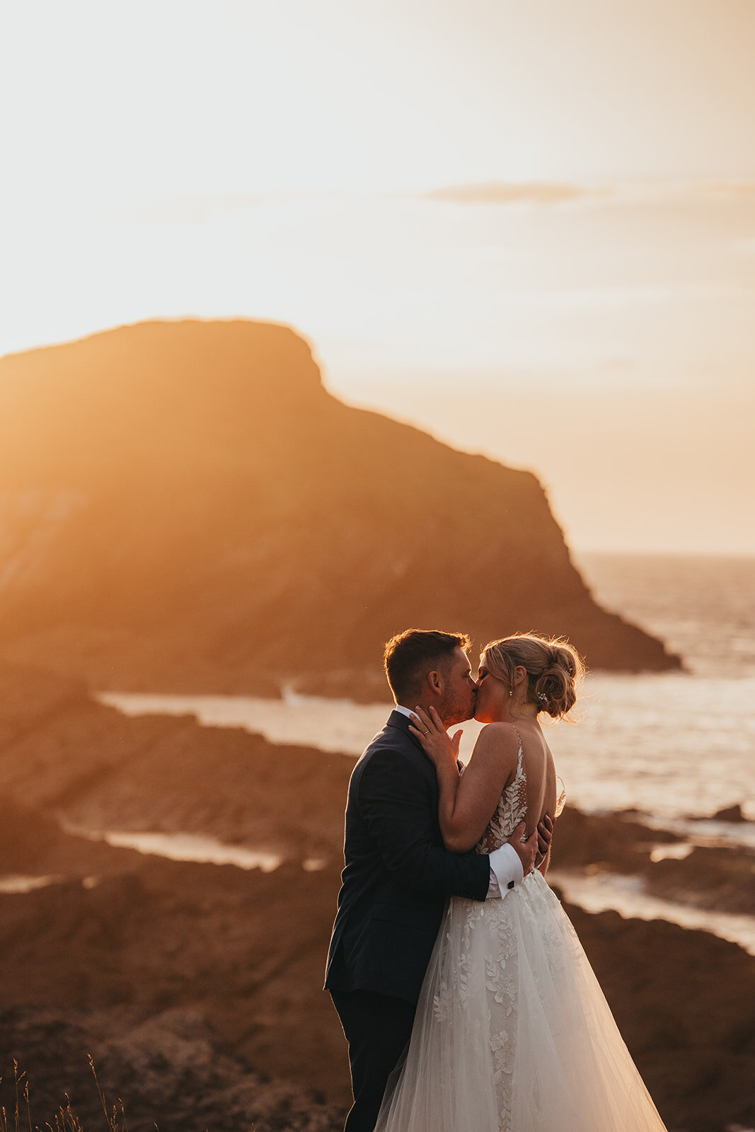 couple kiss on cliffs at sunset