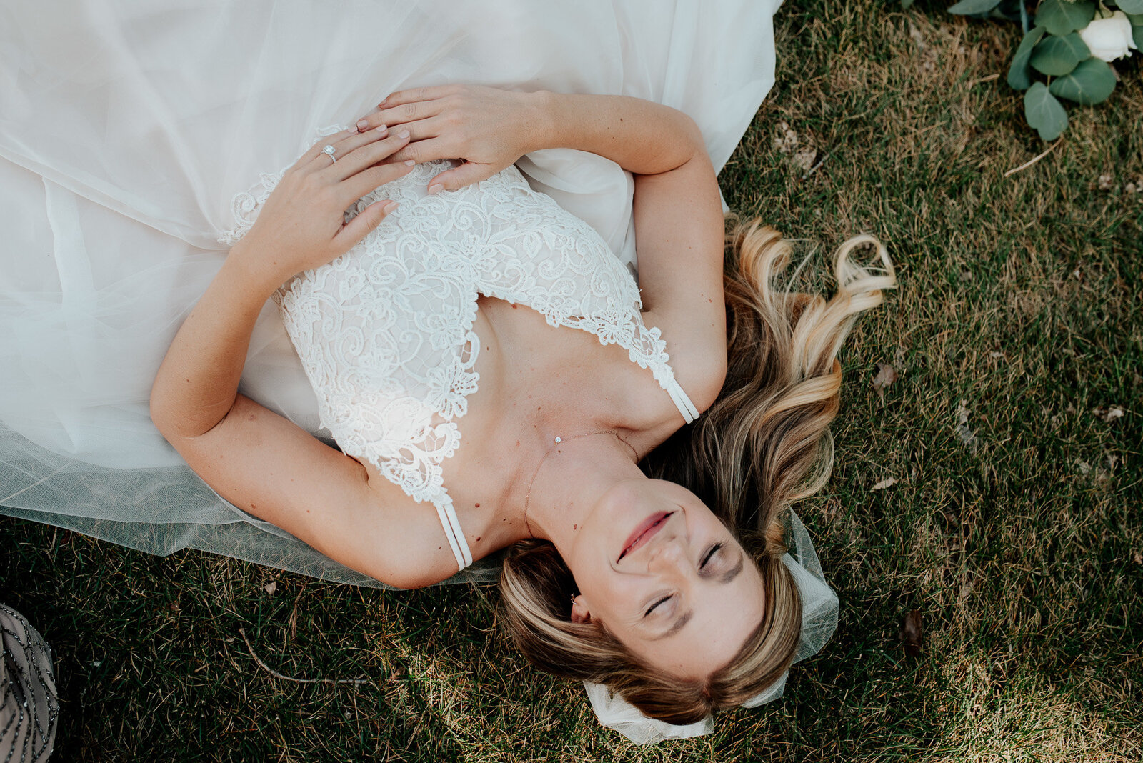 gorgeous photo of a bride laying in the grass on her wedding day at block one events.
