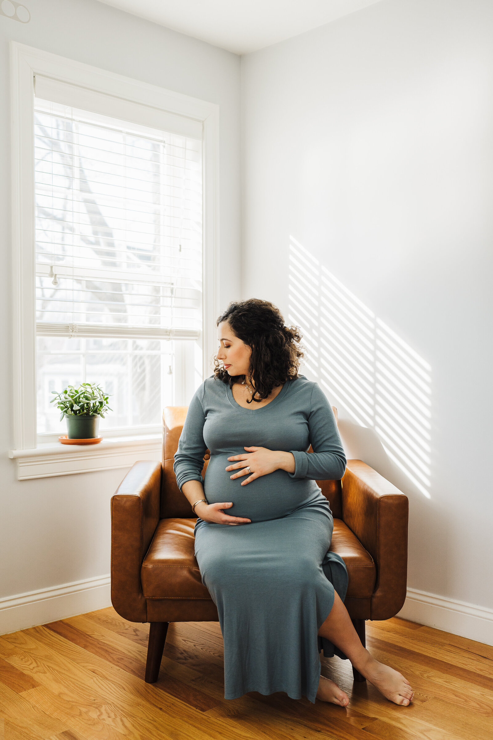 pregnant woman sits in armchair by window