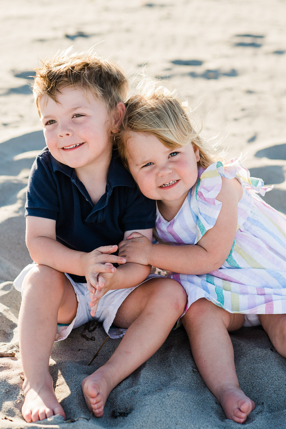 brother and sister snuggle on beach