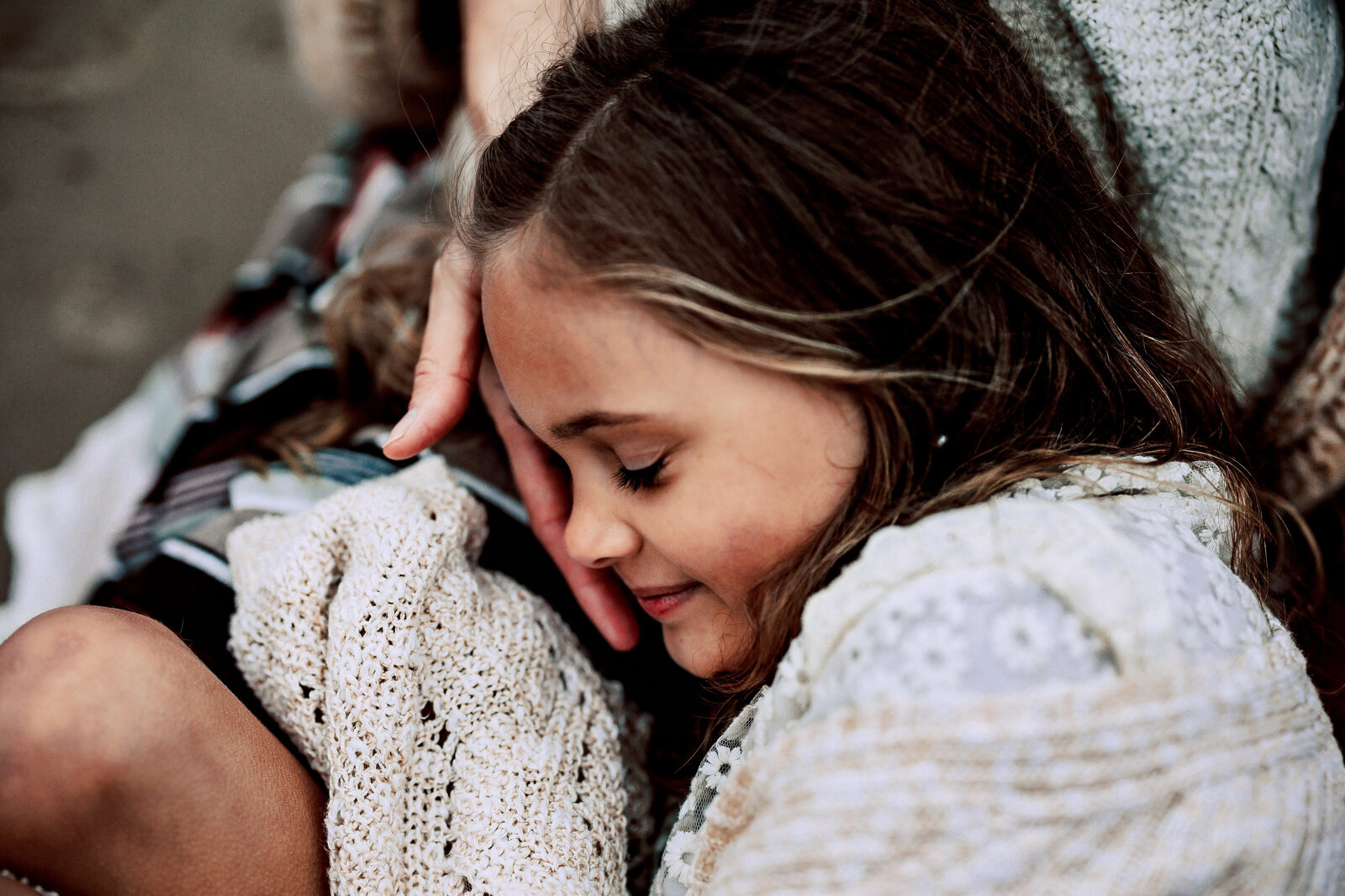 Profile of young girl resting on her mother's lap on the beach in Florida