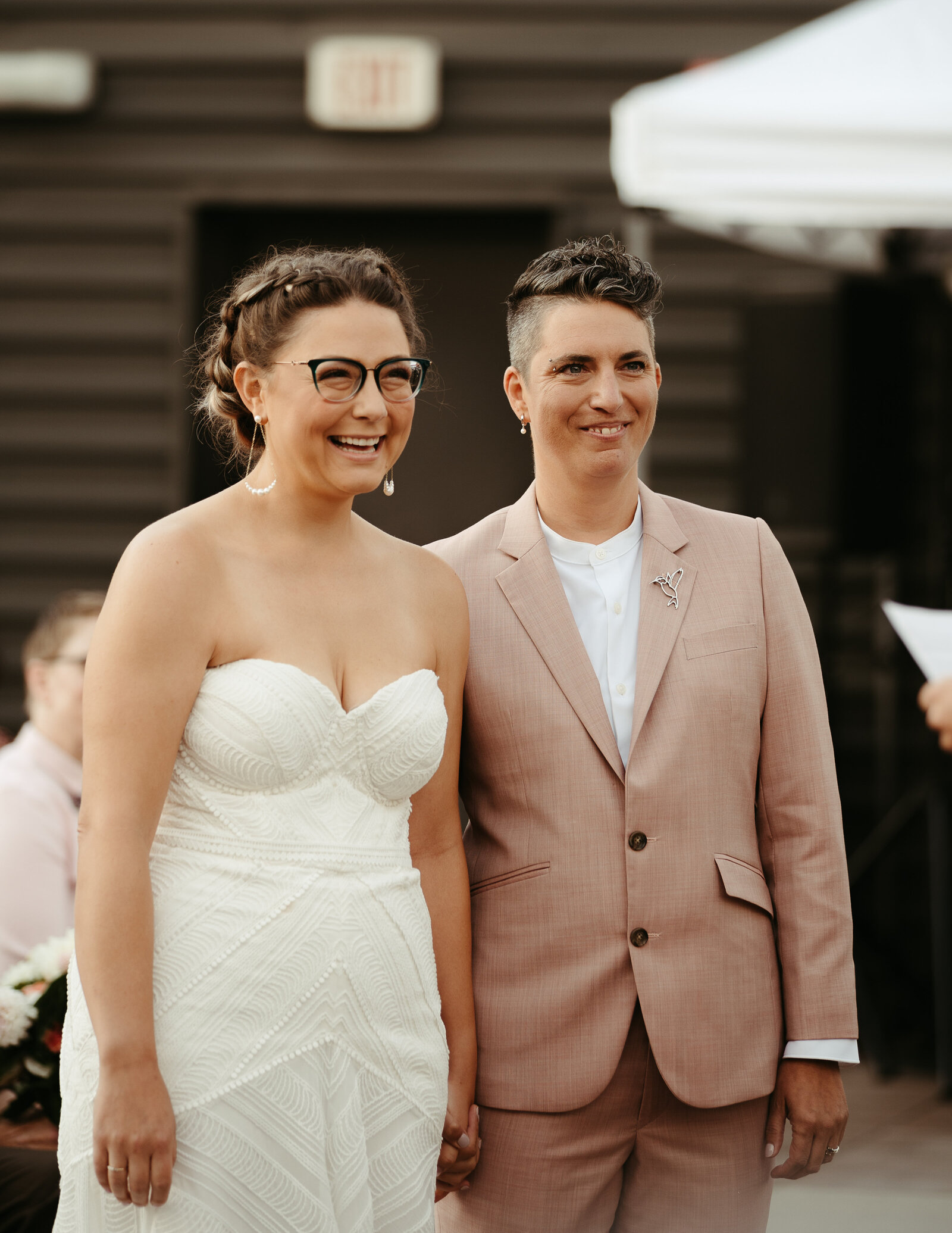 Two brides smiling and holding hands
