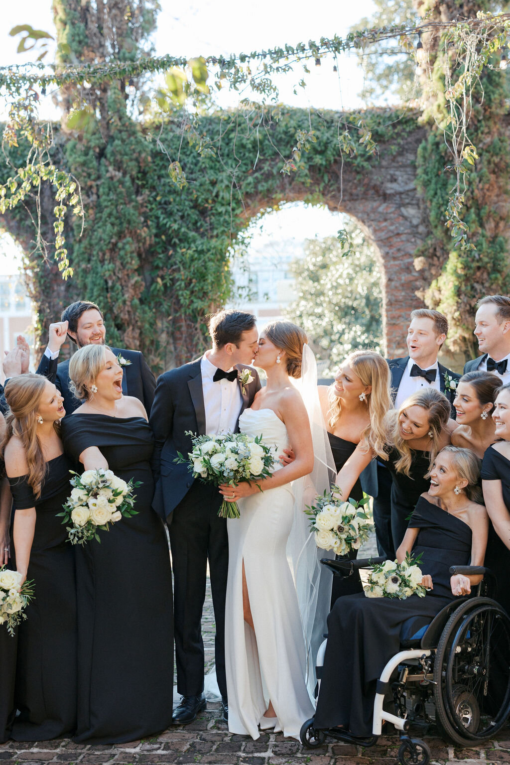 Bride and groom kiss with wedding party outside of Summerour Studio in Atlanta