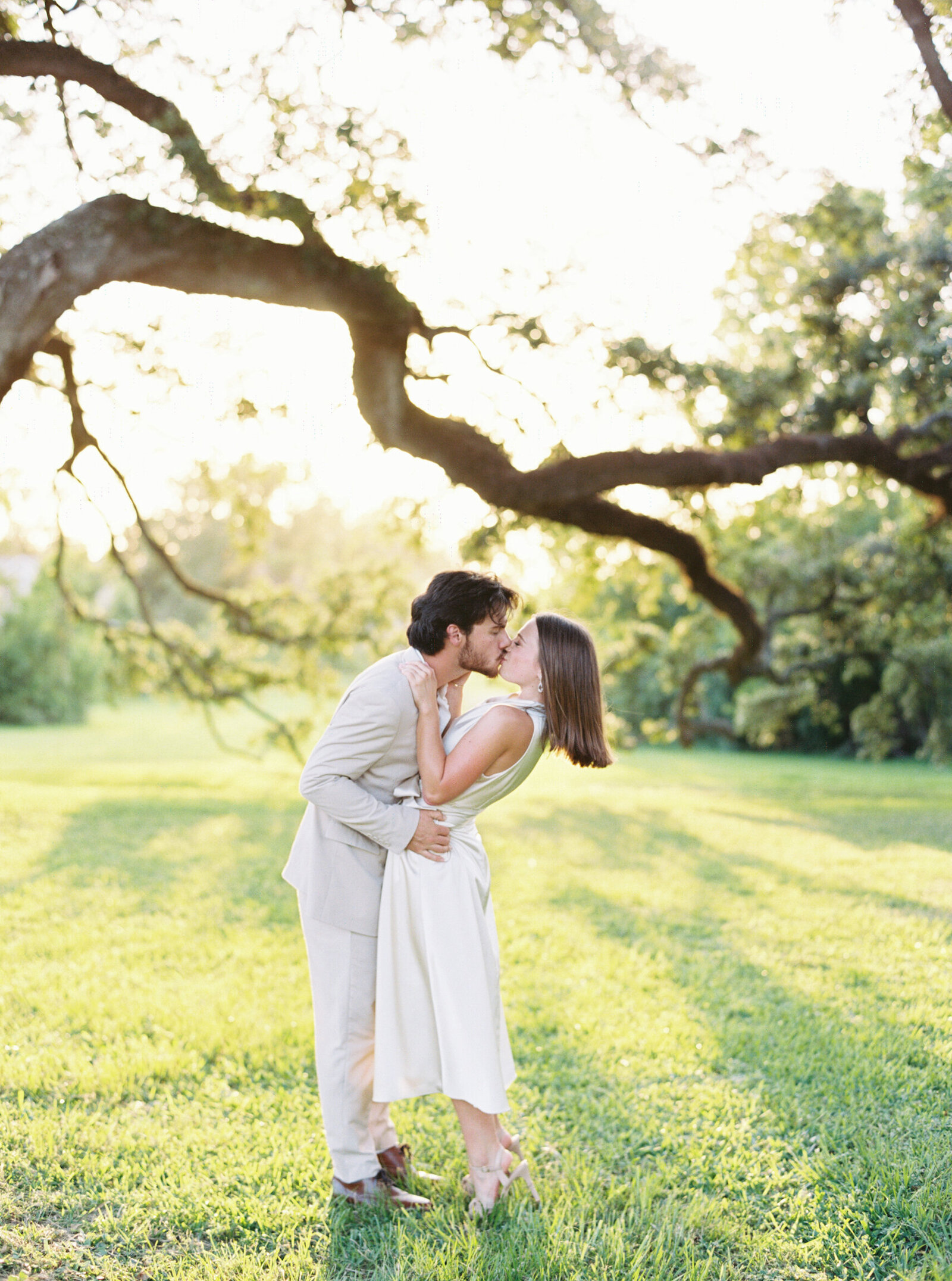 Couple posing for engagement photos under a historic oak tree, captured on film by Morgan Alysse, Louisiana film photographer.