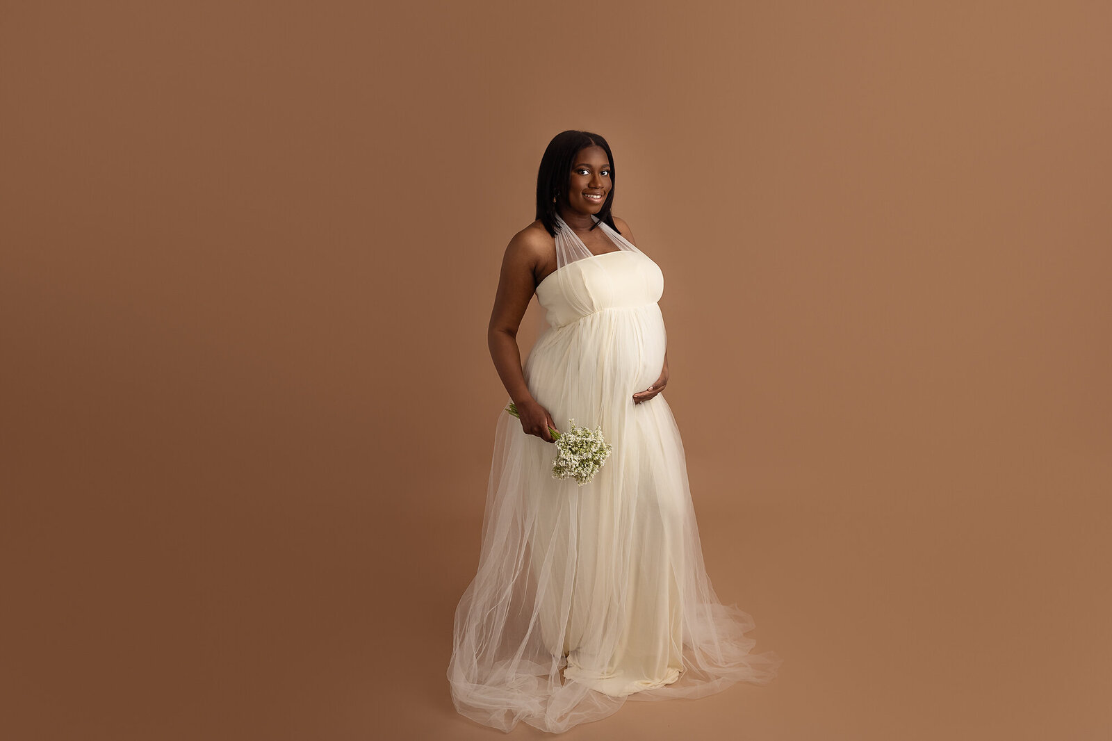 studio portrait of pregnant woman in cream flowy dress