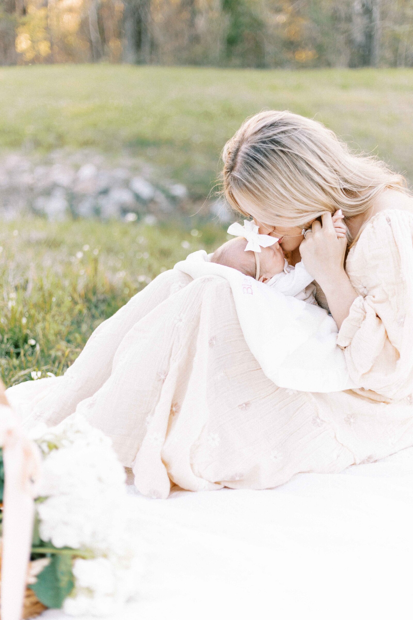 mom with baby on knees kissing her in newborn photos in peoria illinois