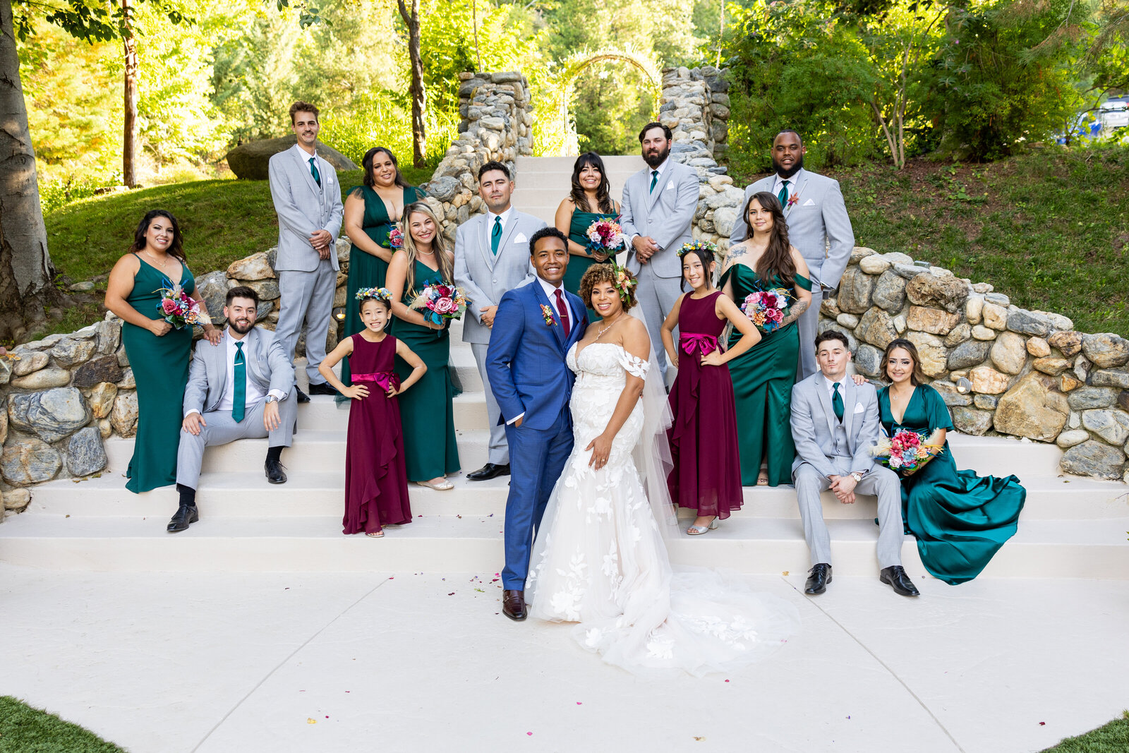 Large wedding party poses for picture with people staggered on stairs and bride and groom standing in the middle. Wedding photo by philippe studio pro, based in Sacramento.