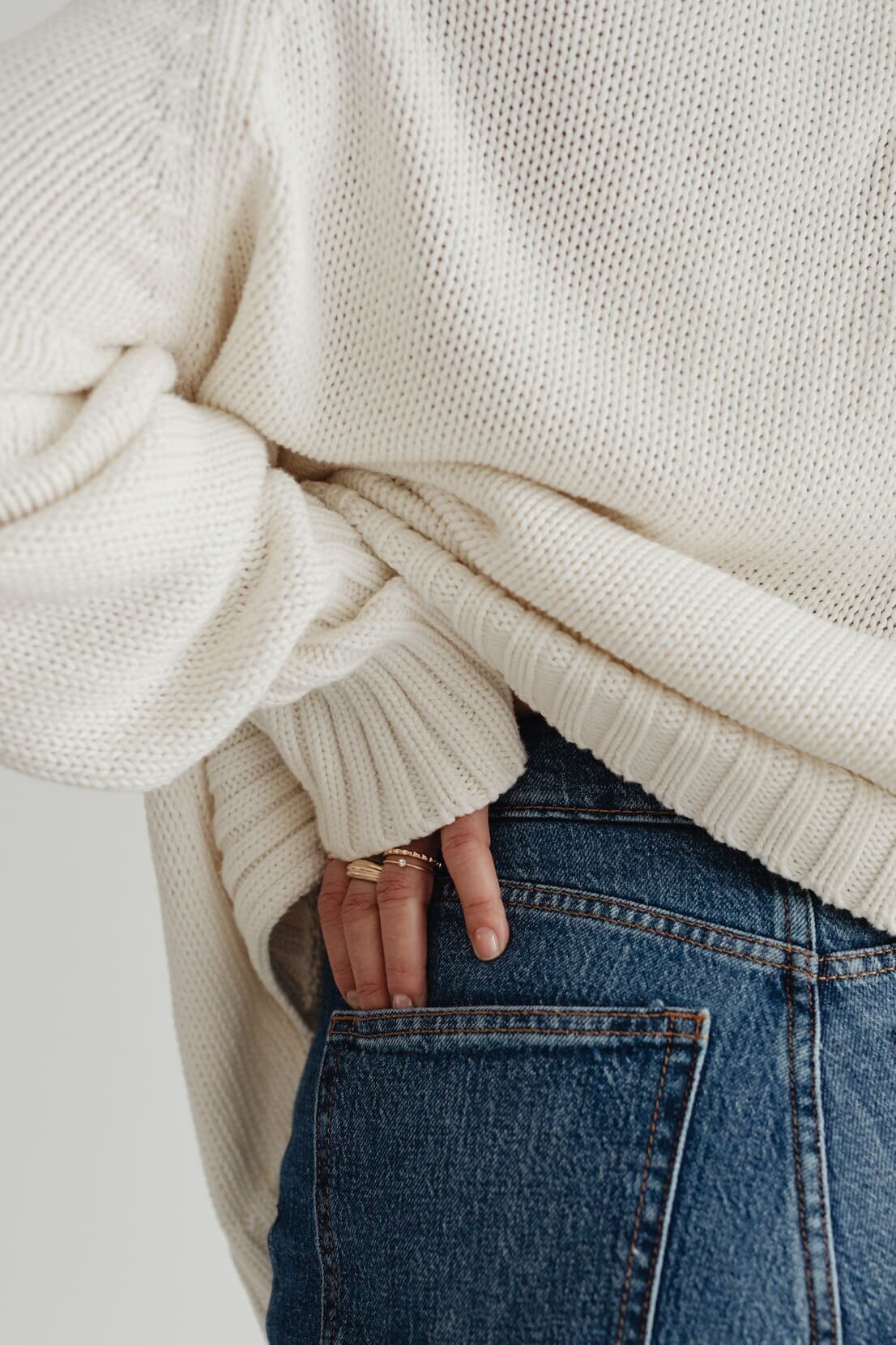 kaboompics_woman-in-white-sweater-gold-rings-jewelry-jeans-29409