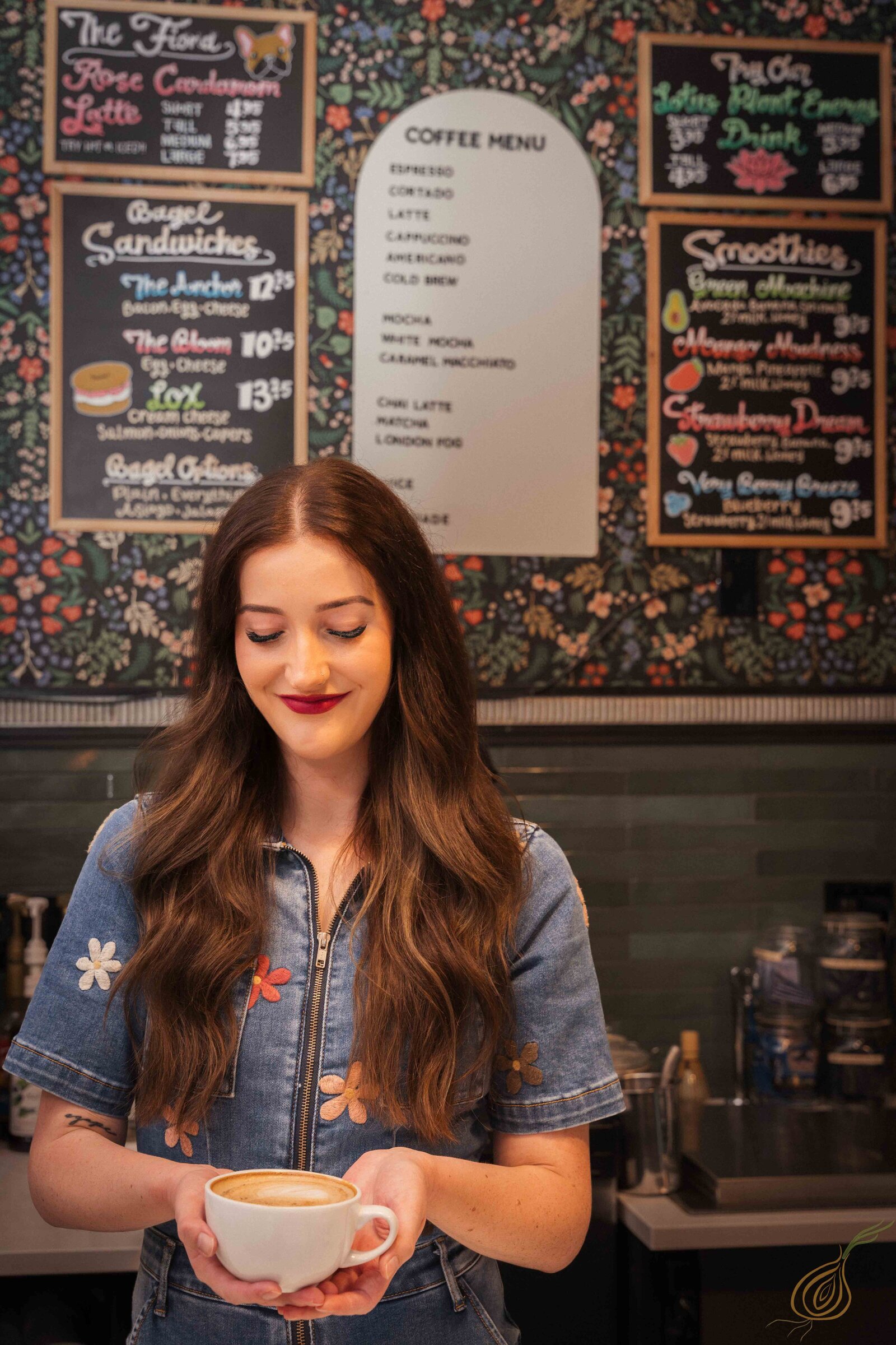 A woman stands with a cup of coffee, thoughtfully in a charming café atmosphere with the coffee menu in the background.