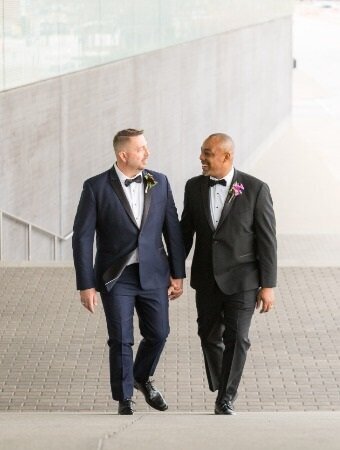 Two grooms hold hands and they come up steps- Figge Art Museum