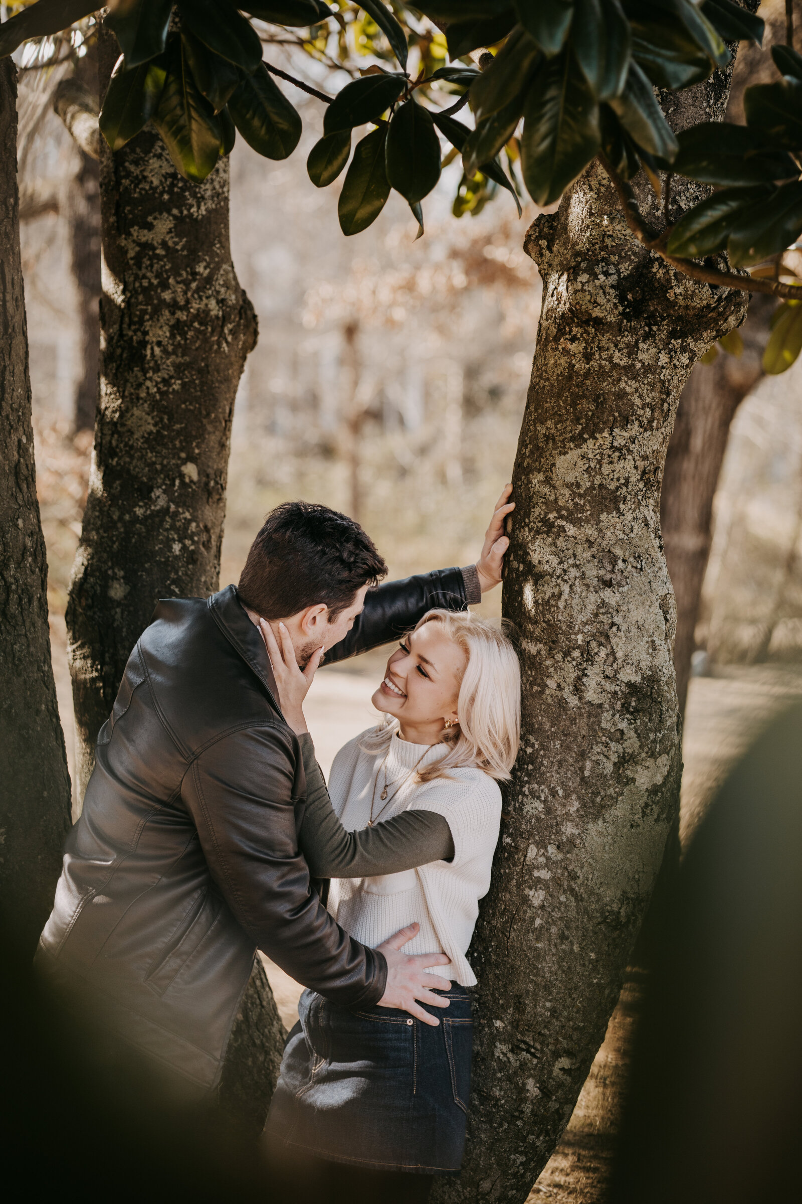 Engagement session with Rachel and Blaine, captured through tree leaves as they hold each other, about to kiss.