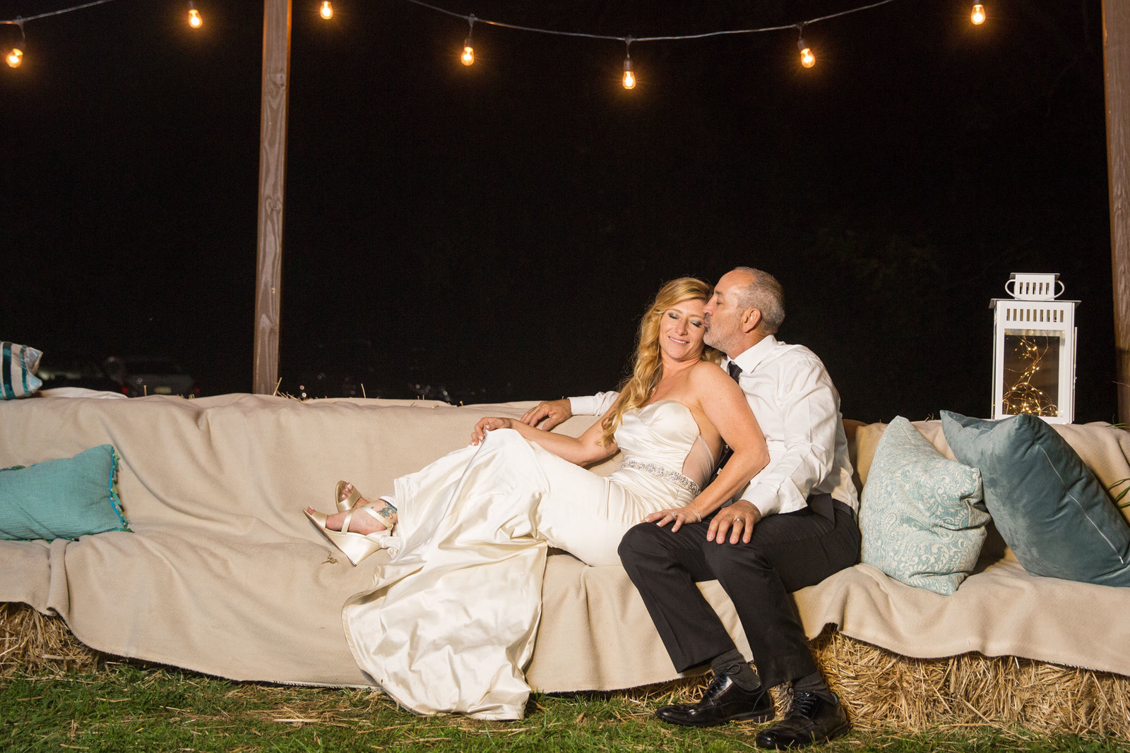 bride and groom sitting on the couch outside George Weir Barn at night
