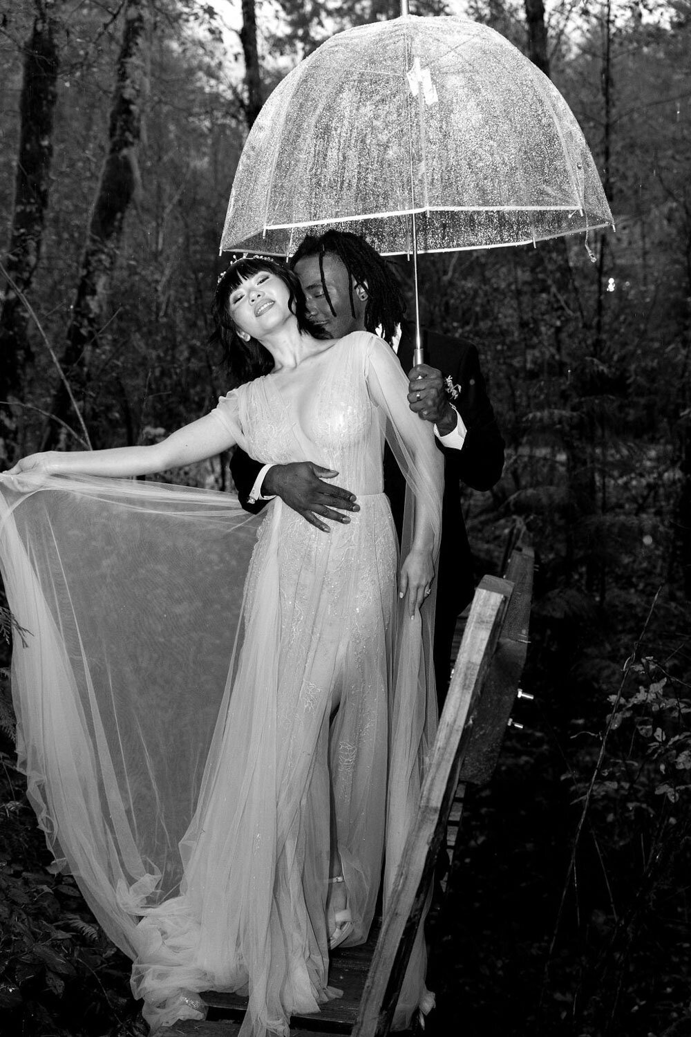 Bride spinning her dress with the groom holding an umbrell