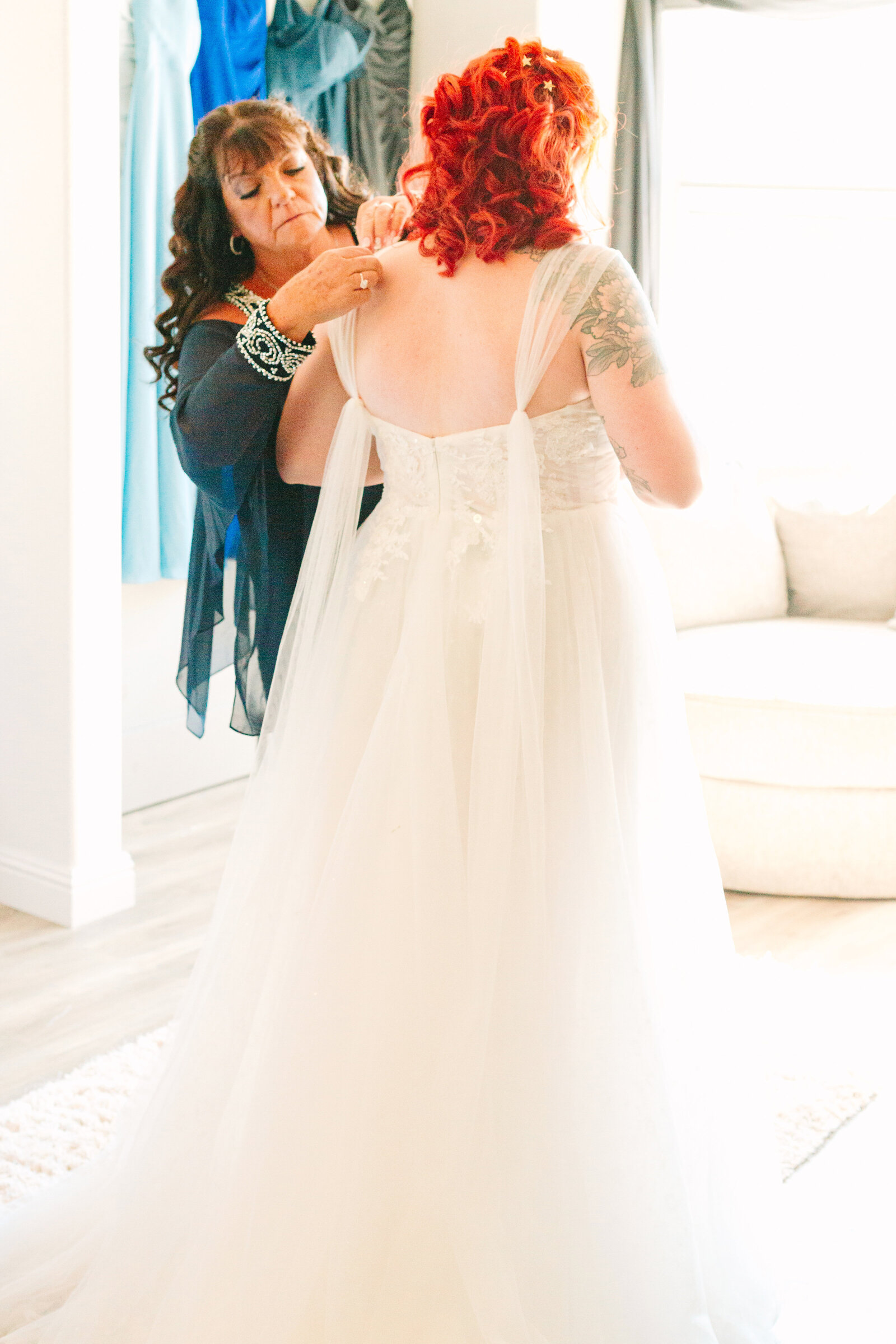A bride with red hair and tattoos gets ready on her wedding day with her from her mother.