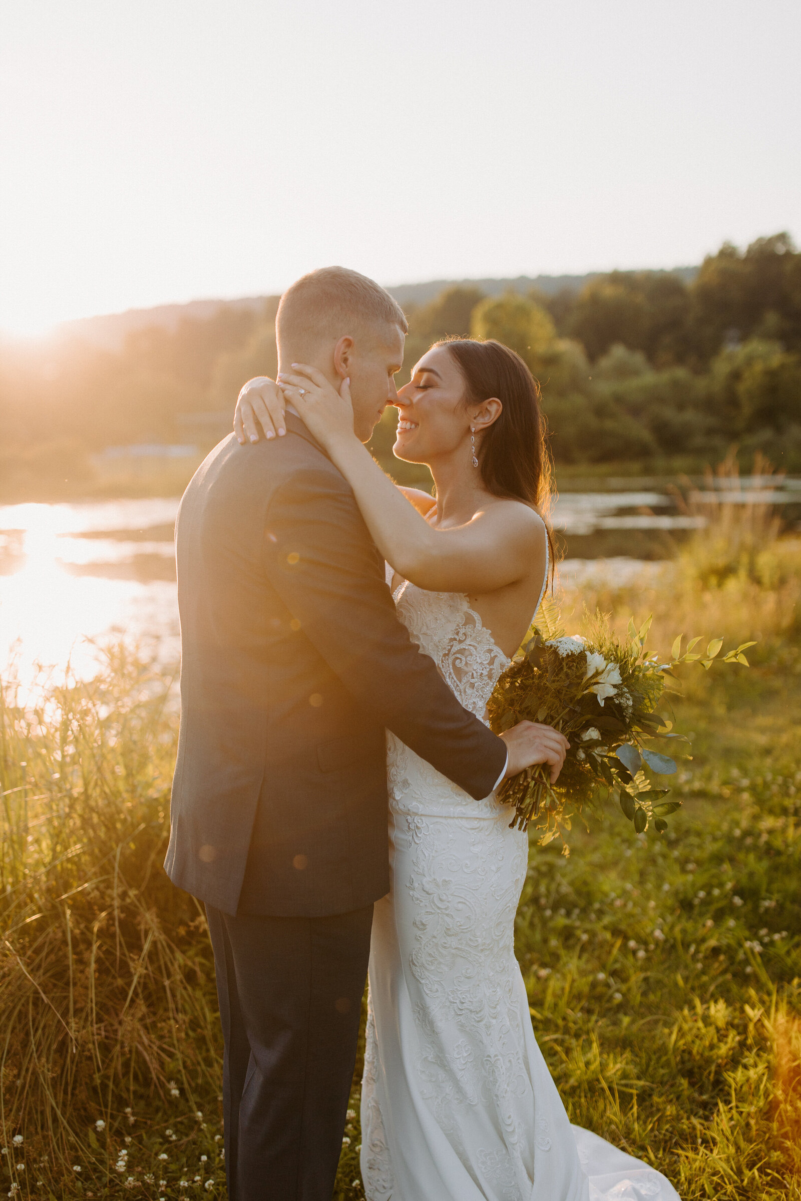 bride and groom with their arms around each other about to kiss at sunset