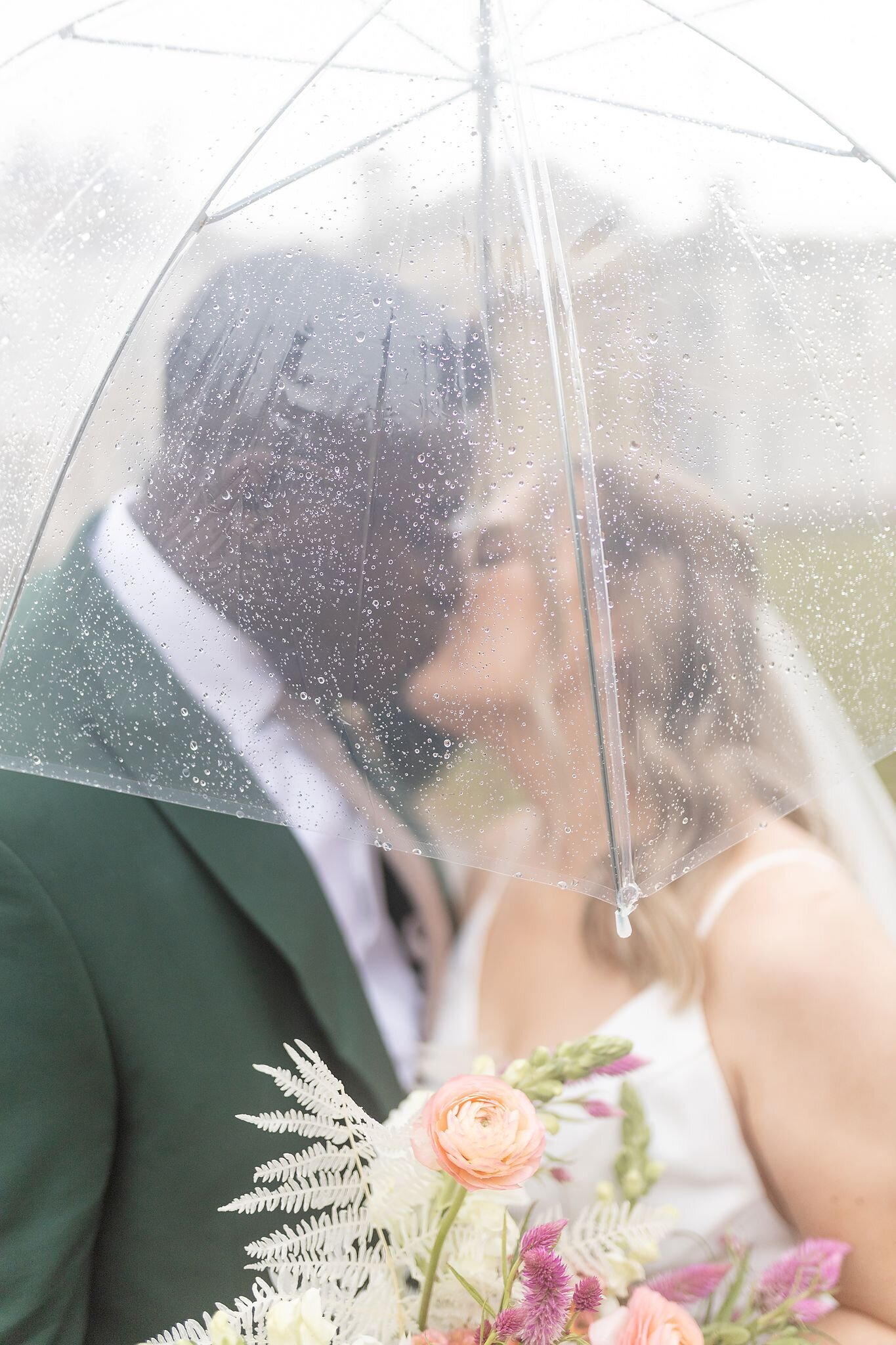 Bride-and-groom-kiss-under-an-umbrella-on-their-wedding-day-at-dundurn-castle-in-hamilton-ontario