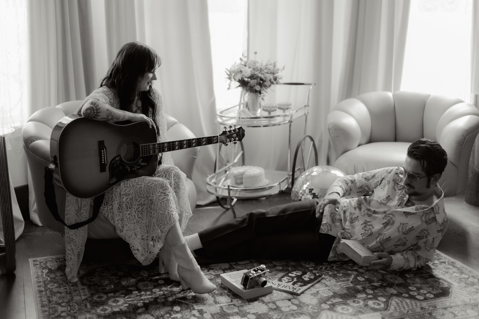 Black and white editorial bridal portrait with a retro romantic aesthetic, featuring a bride posing with a vintage guitar to create a cinematic, music-inspired moment.