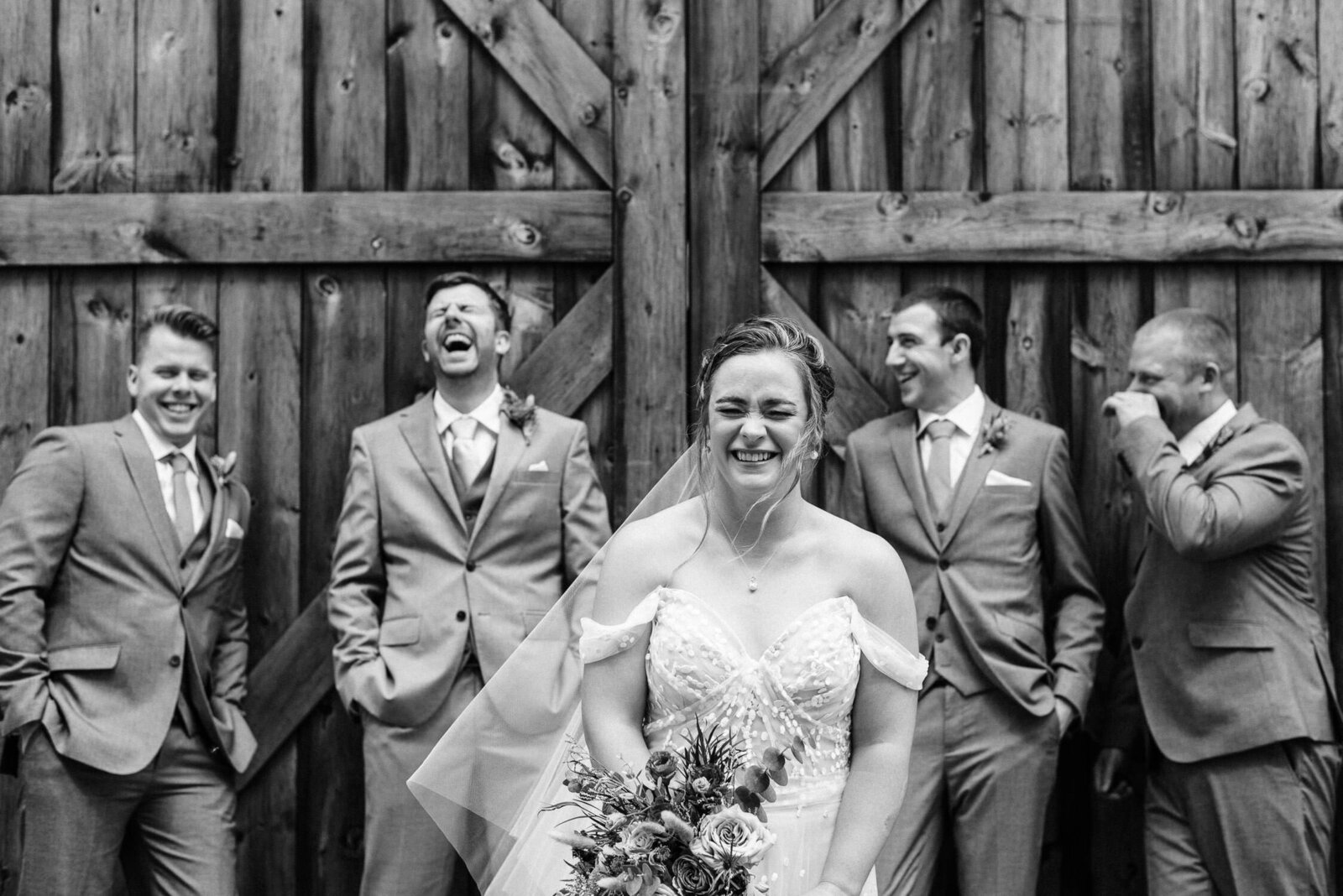 Bride and groomsmen laughing at Nova Scotia barn wedding.