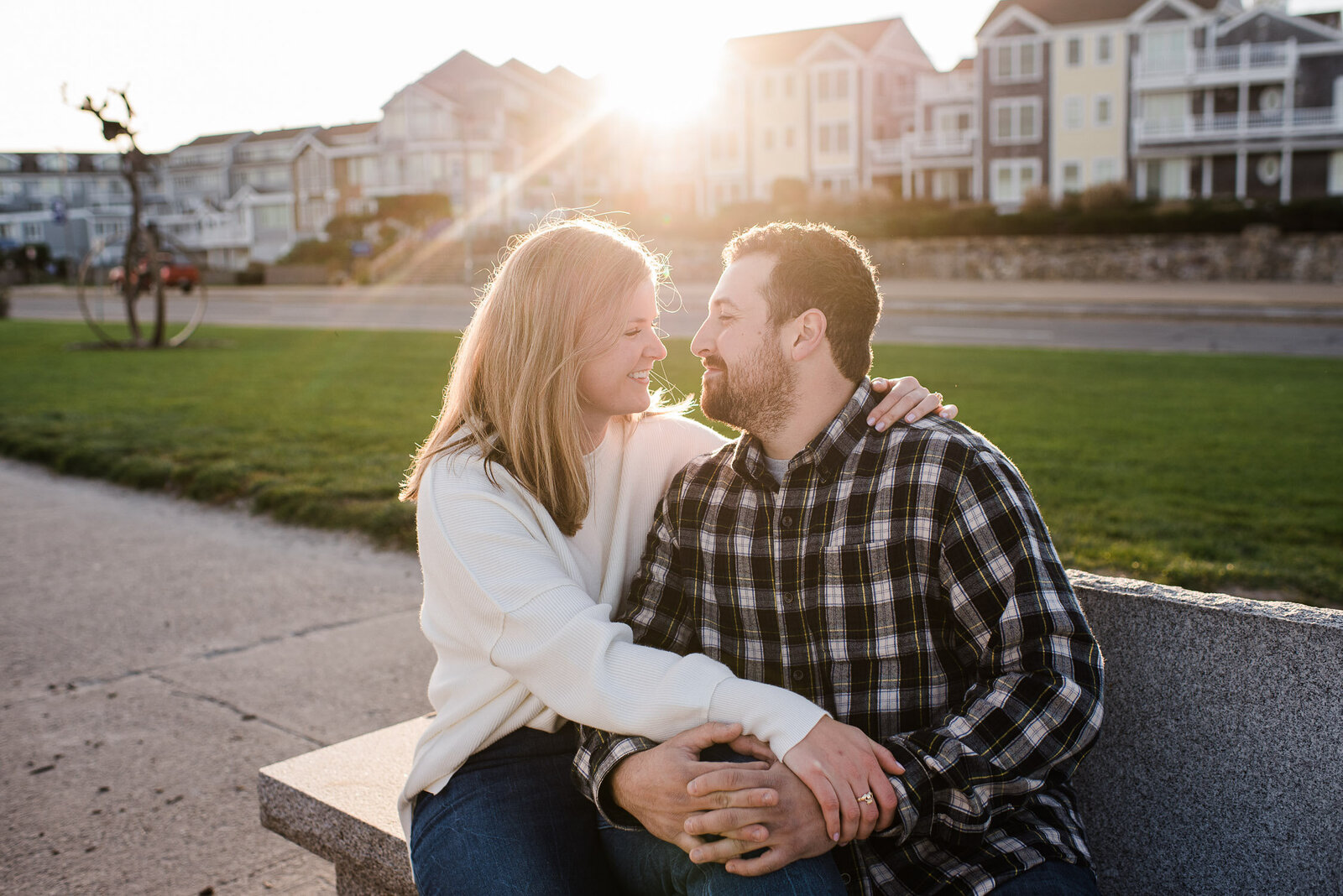 couple sitting on bench looking at each other in sunlight