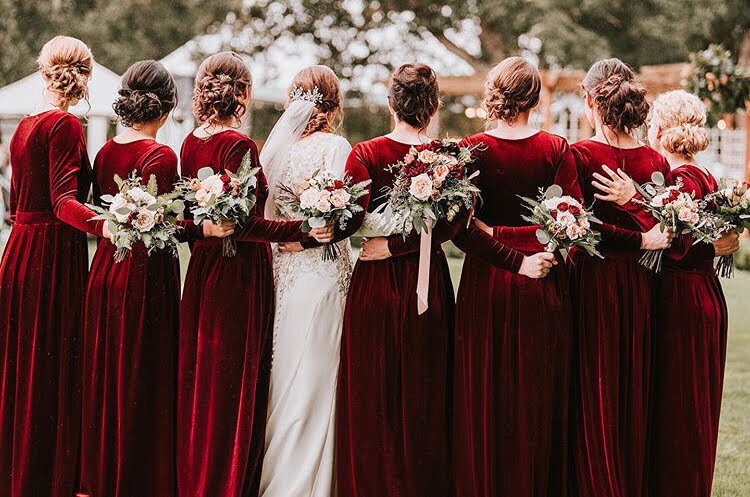 Bridal party holds their bouquets with arms around each other's backs, representing an example of work from the florist portfolio for Flowers and Thyme.