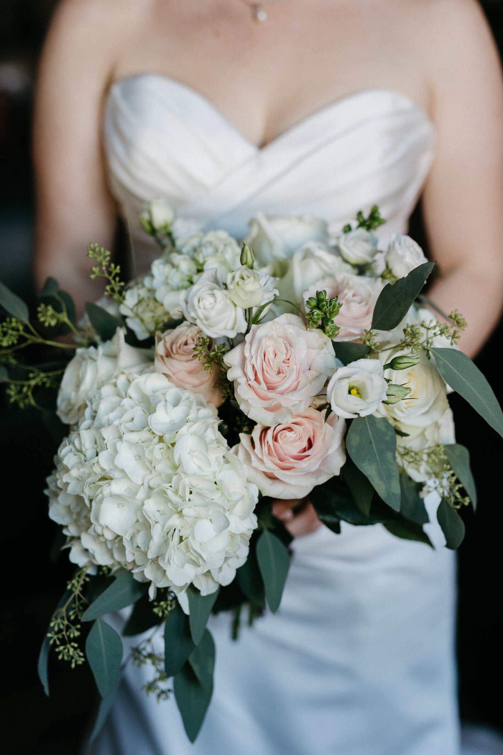 A bride holds her bouquet in front of her wedding dress