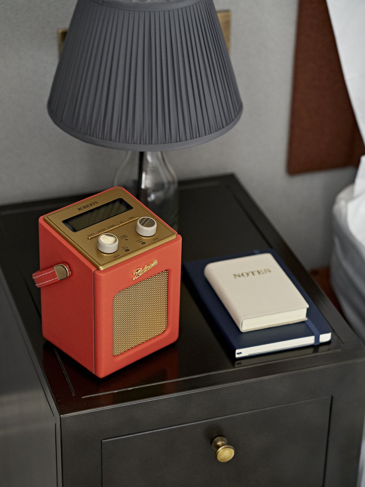 Bedside table detail with notebooks and red radio