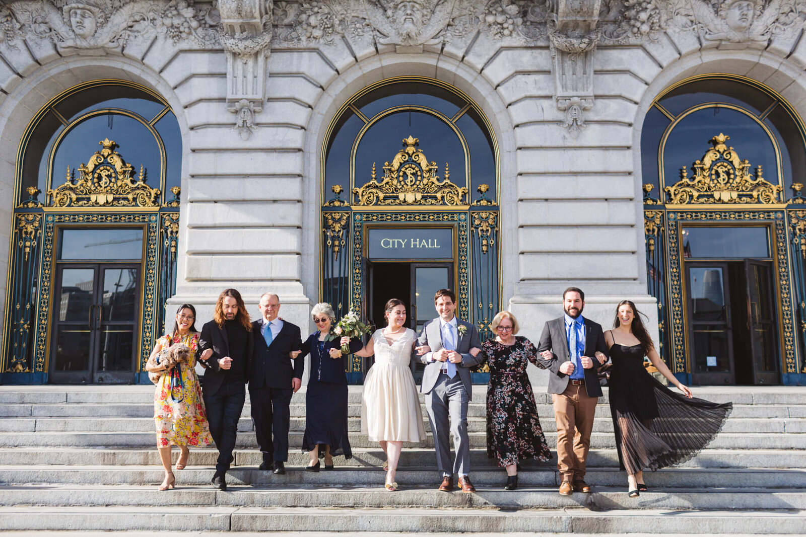 big wedding group walking down steps of San Francisco City Hall