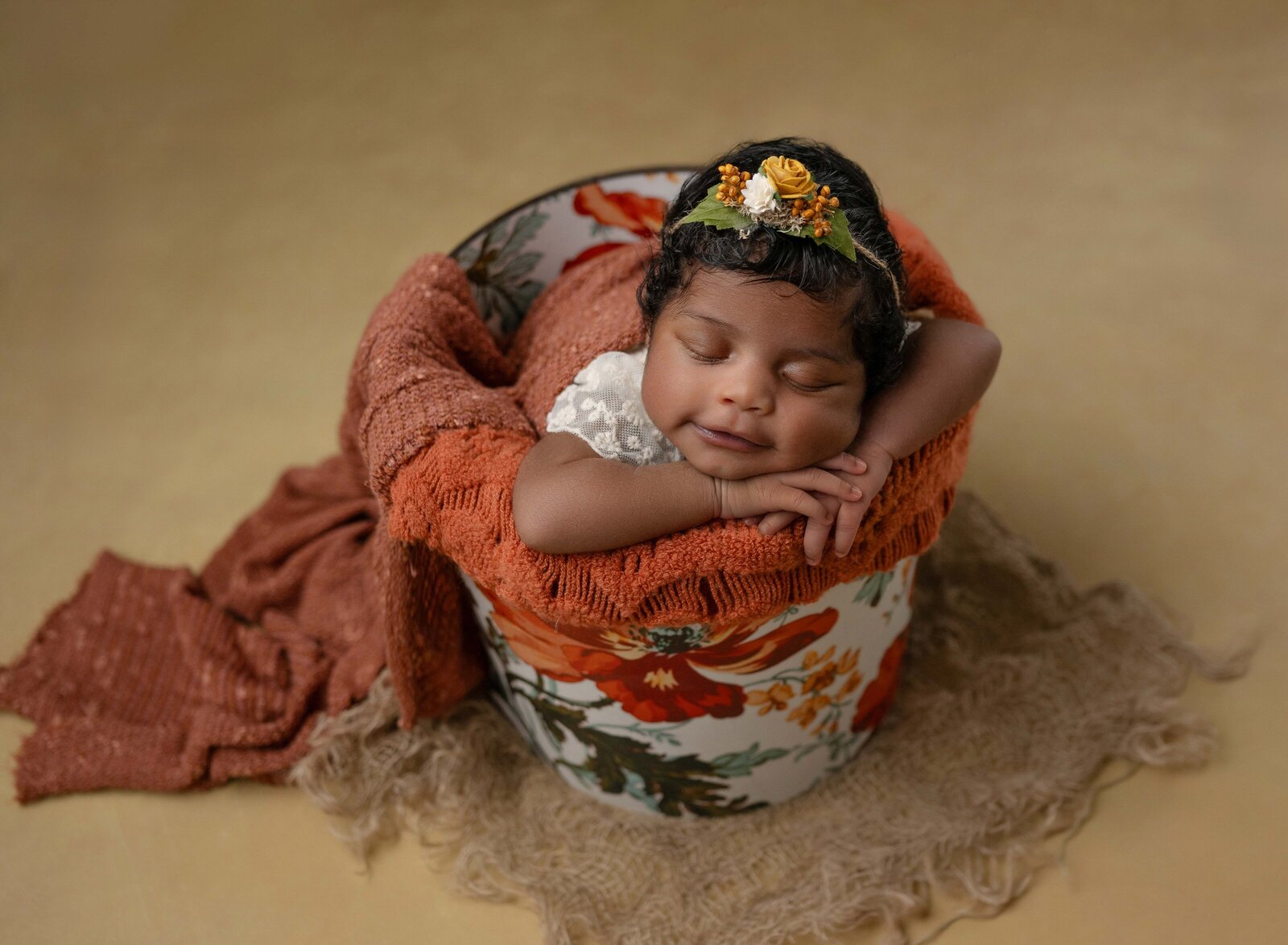 Baby girl lying in floral bucket and smiling. Newborn Photography in Marietta GA by Jenni Nikki Photography.