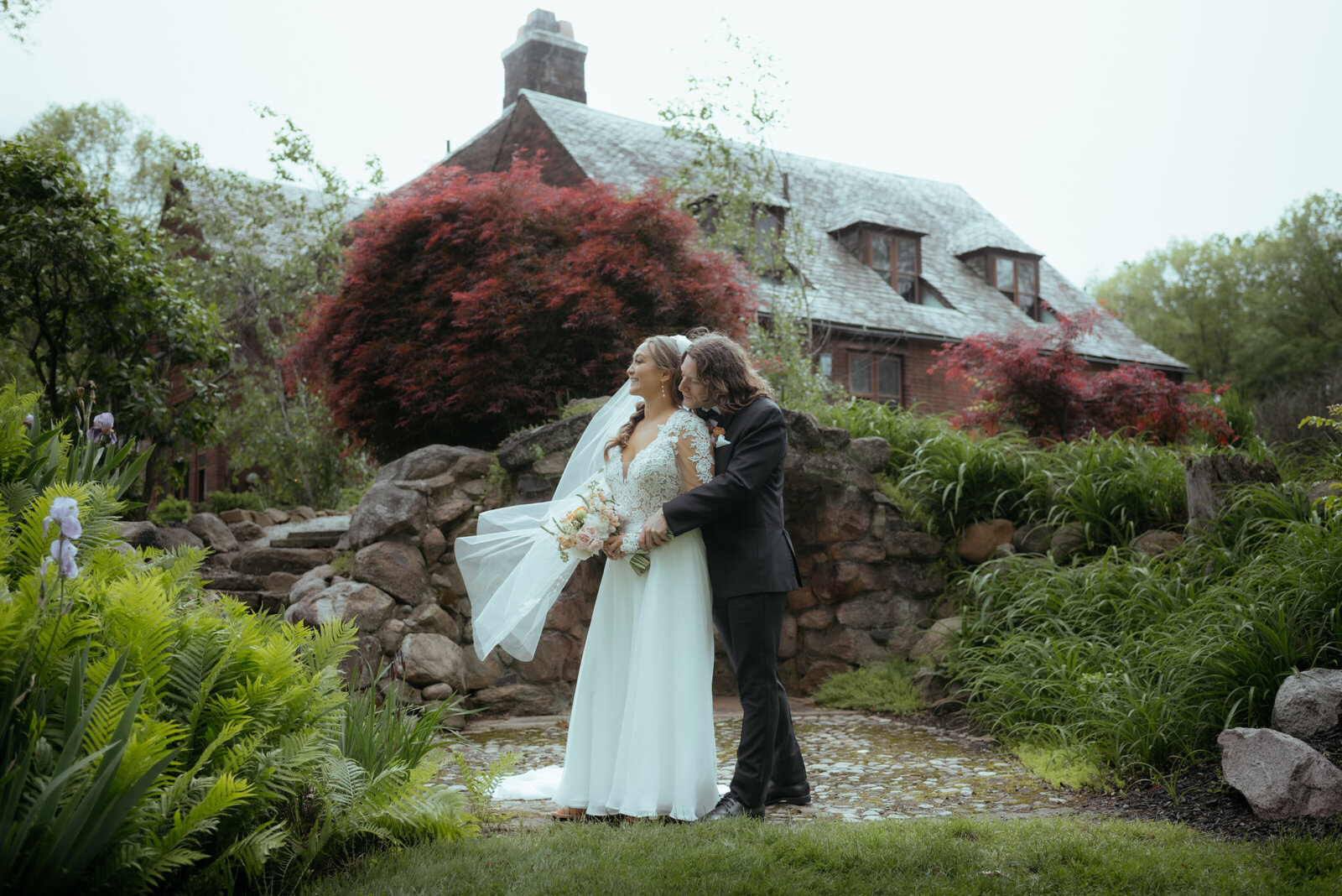 A couple pose together after their First Look in the garden of the Tudor House at Mason's Cove in Akron, Ohio.