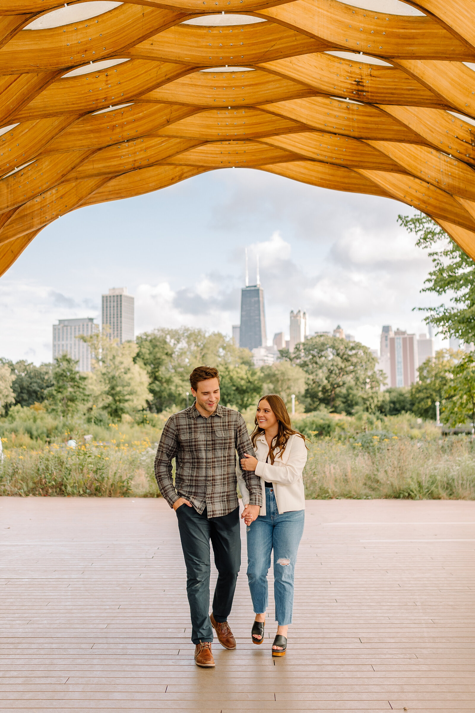 Young couple walking together while hugging each other under the honeycomb sculpture in Chicago