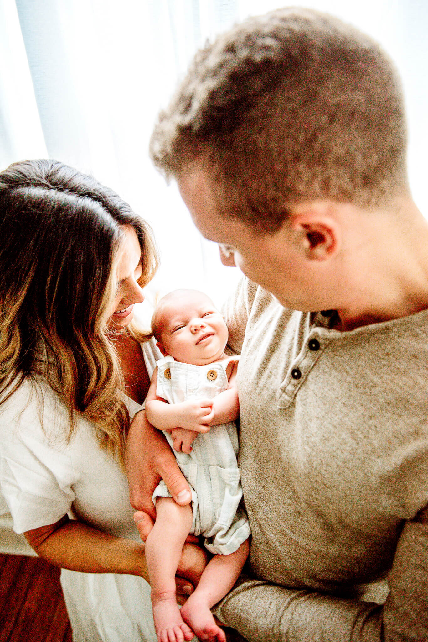 baby smiling while parents hold him