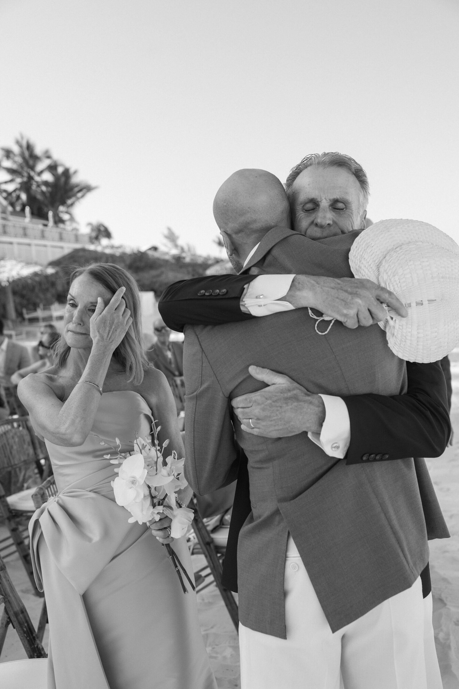 Candid black & white photo of parents hugging groom at ceremony in the Bahamas 
