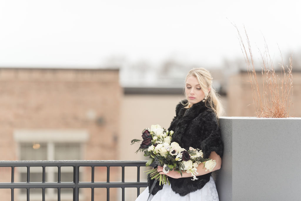 Winter bride wearing a black fur coat on a rooftop
