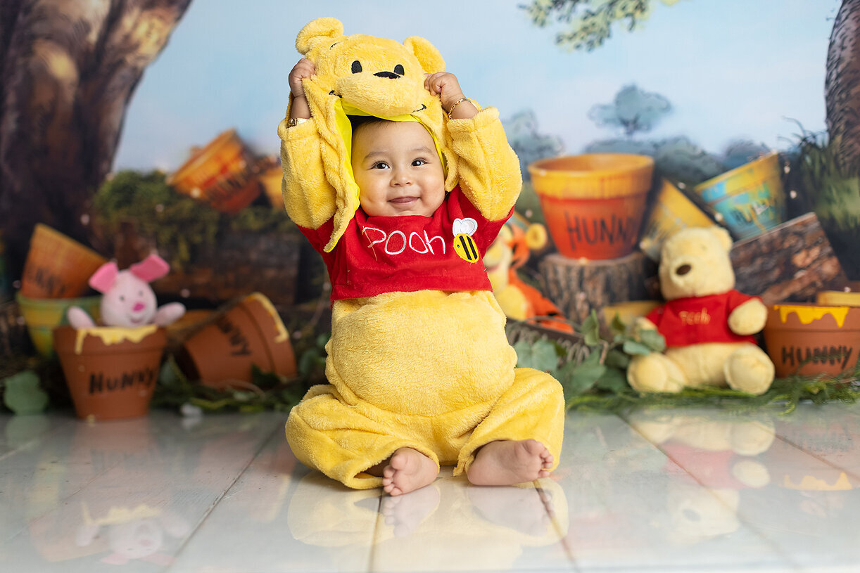 Baby boy dressed and Winnie the Pooh at his cake smash.