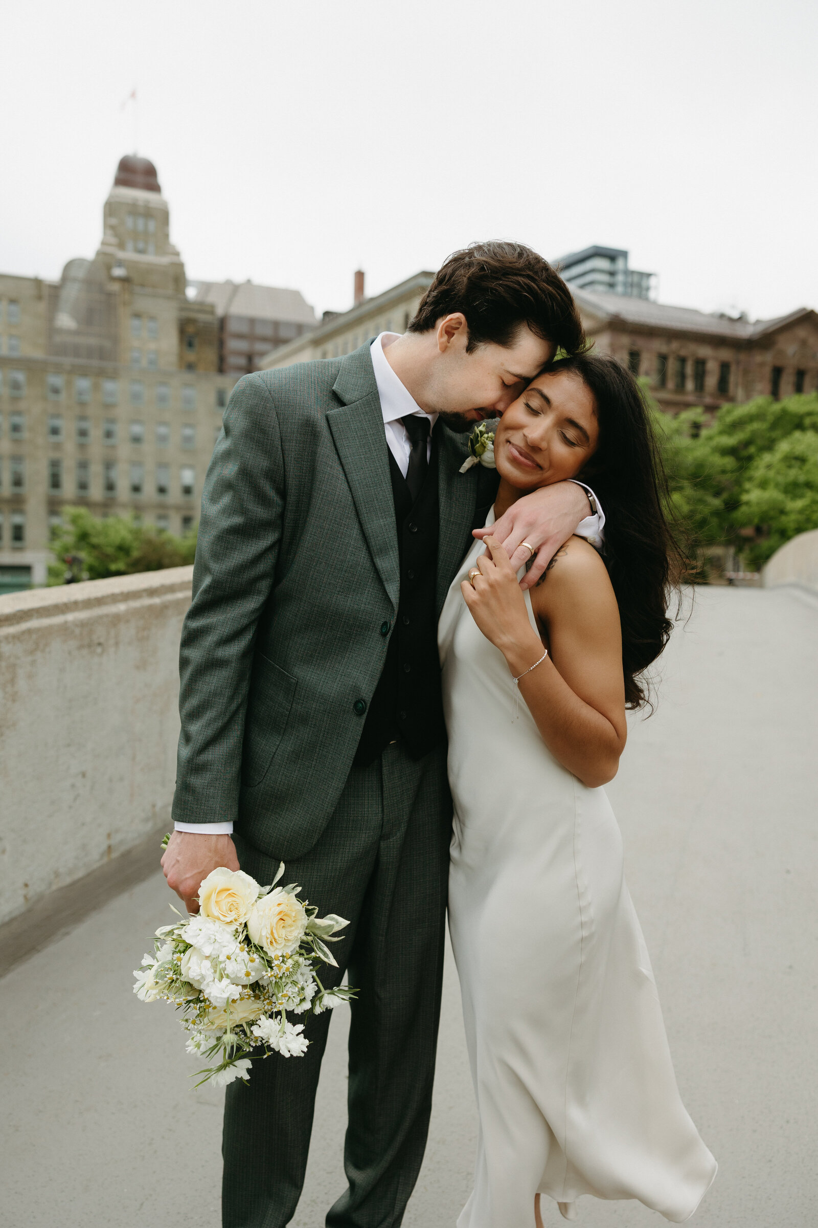 A bride and groom pose together on a pedway in Halifax after eloping at city hall.