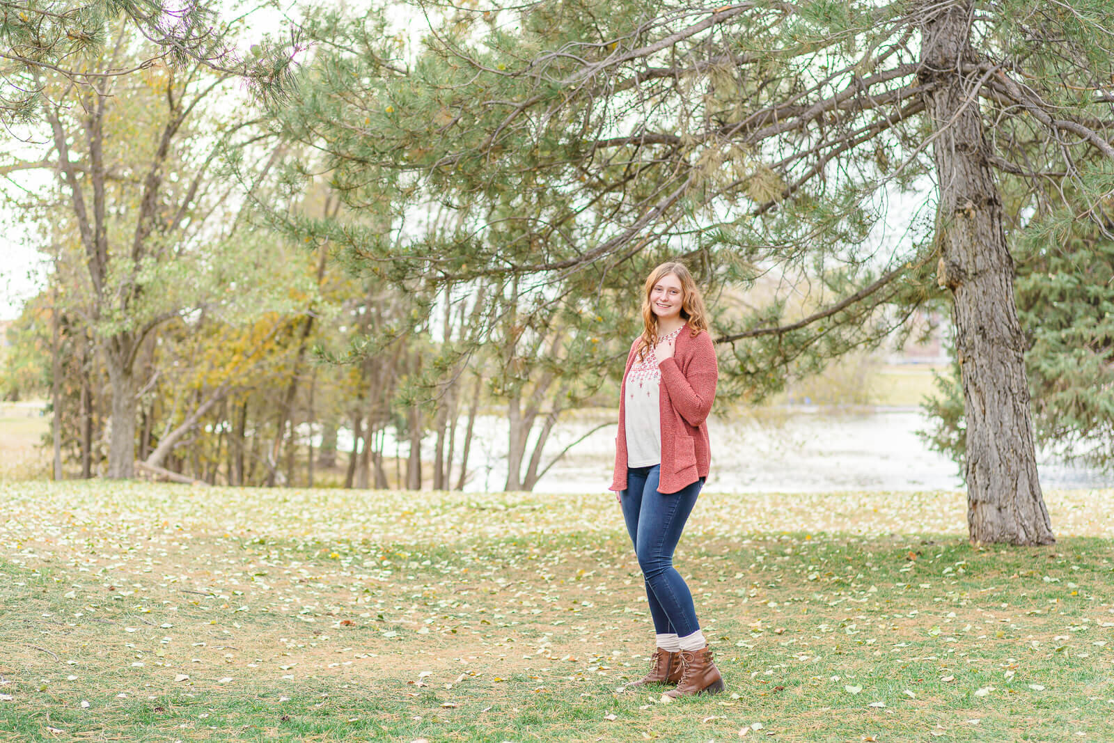 Salt Lake City senior photography of a high school senior girl standing in a grassy field in front of the pond at Sugar House park in the fall