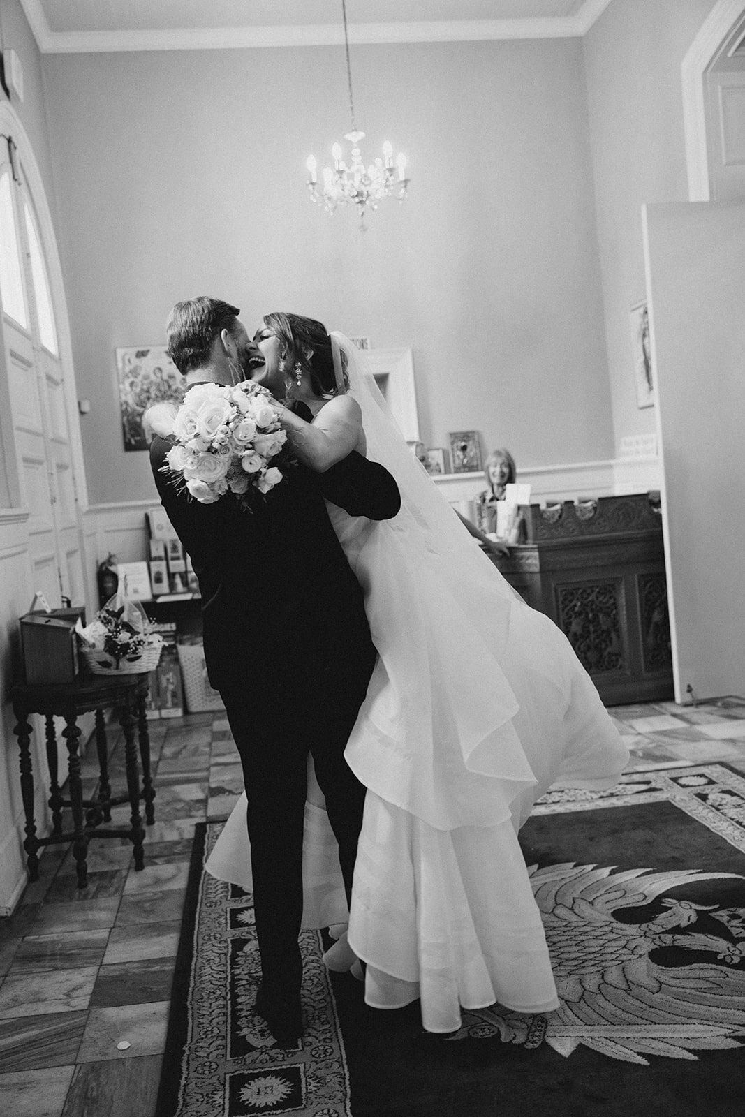 Bride jumping into groom's arms holding bouquet right after saying I do in Greek orthodox church in Macon Georgia