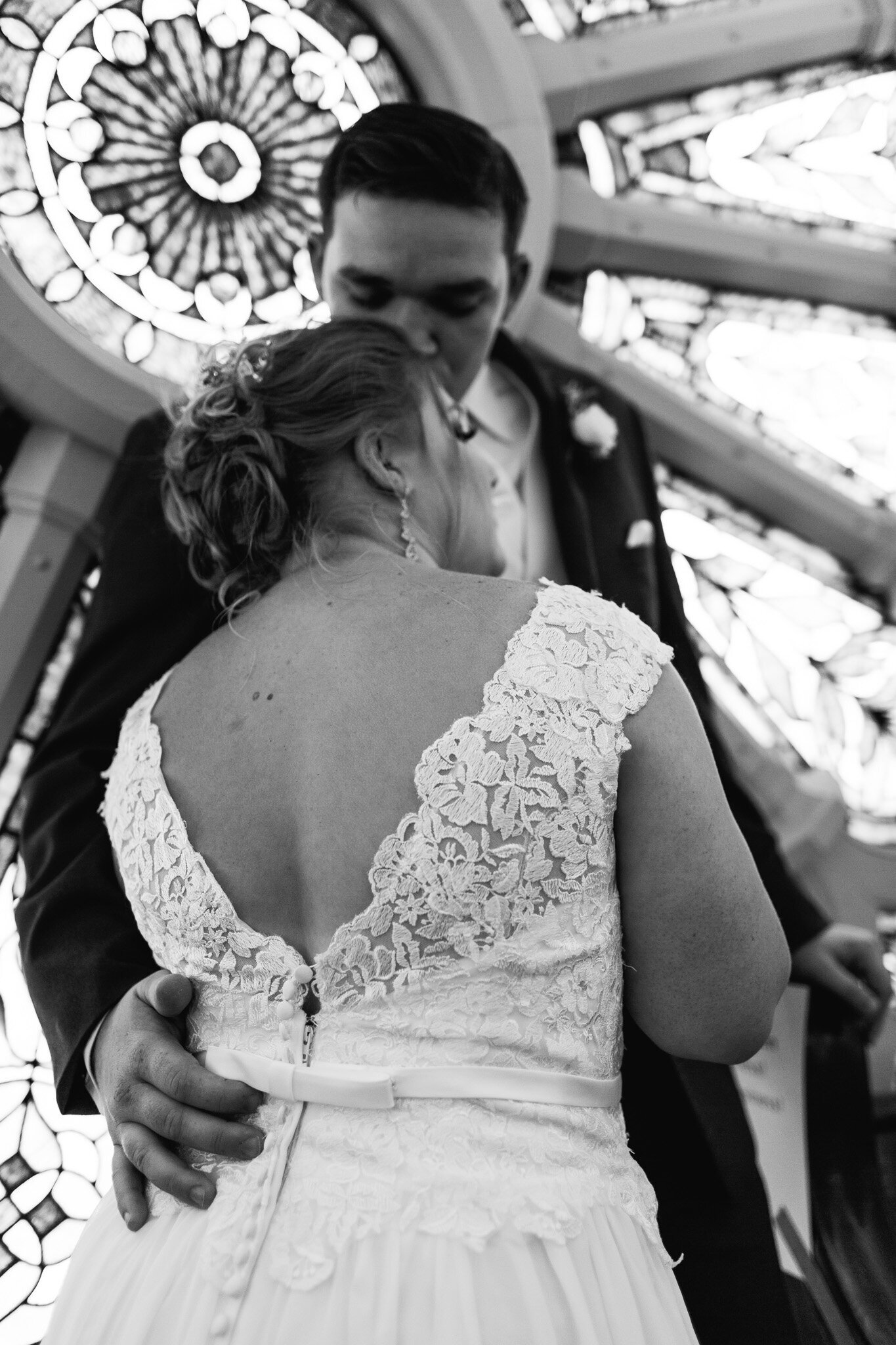 bride and groom embrace in front of old stained glass window in ohio