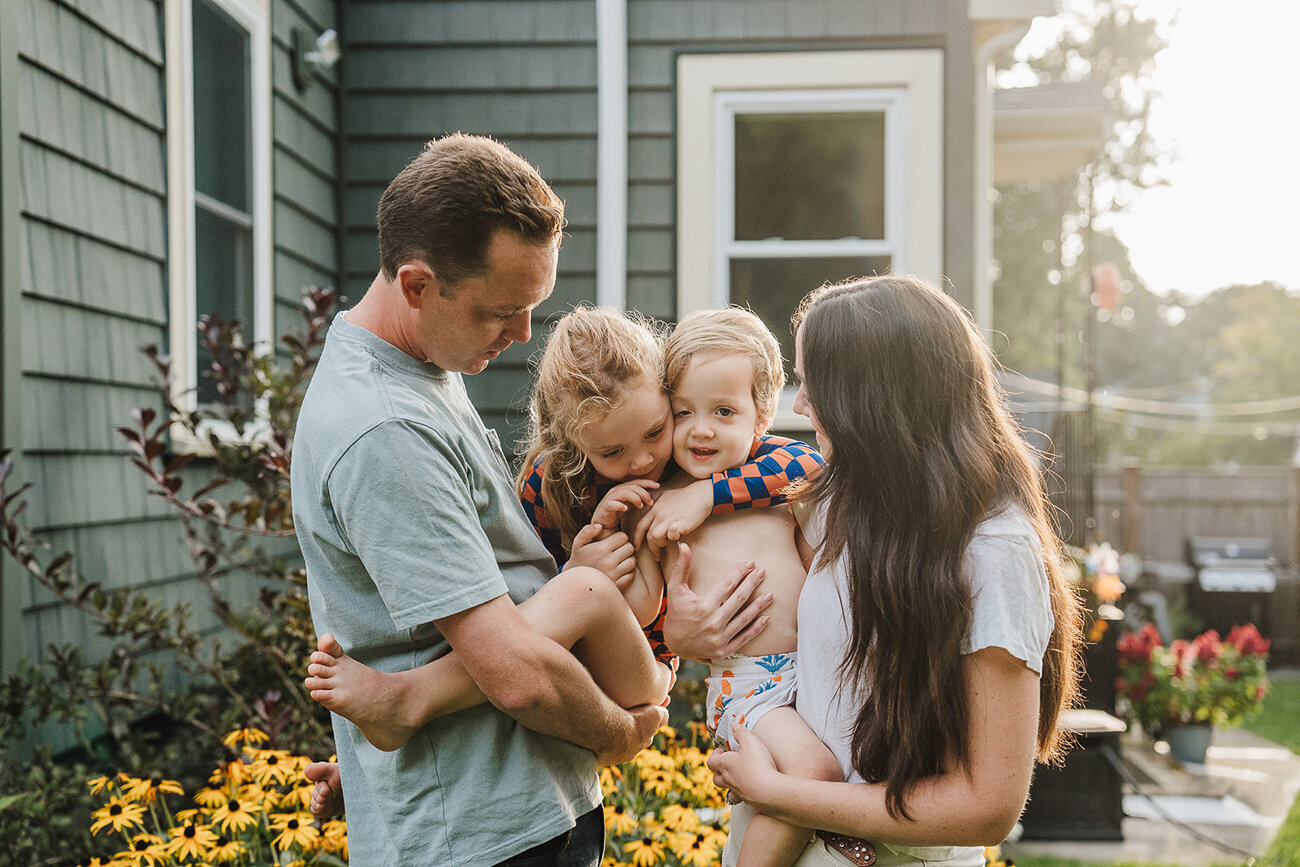 family of four snuggles together in backyard in boston