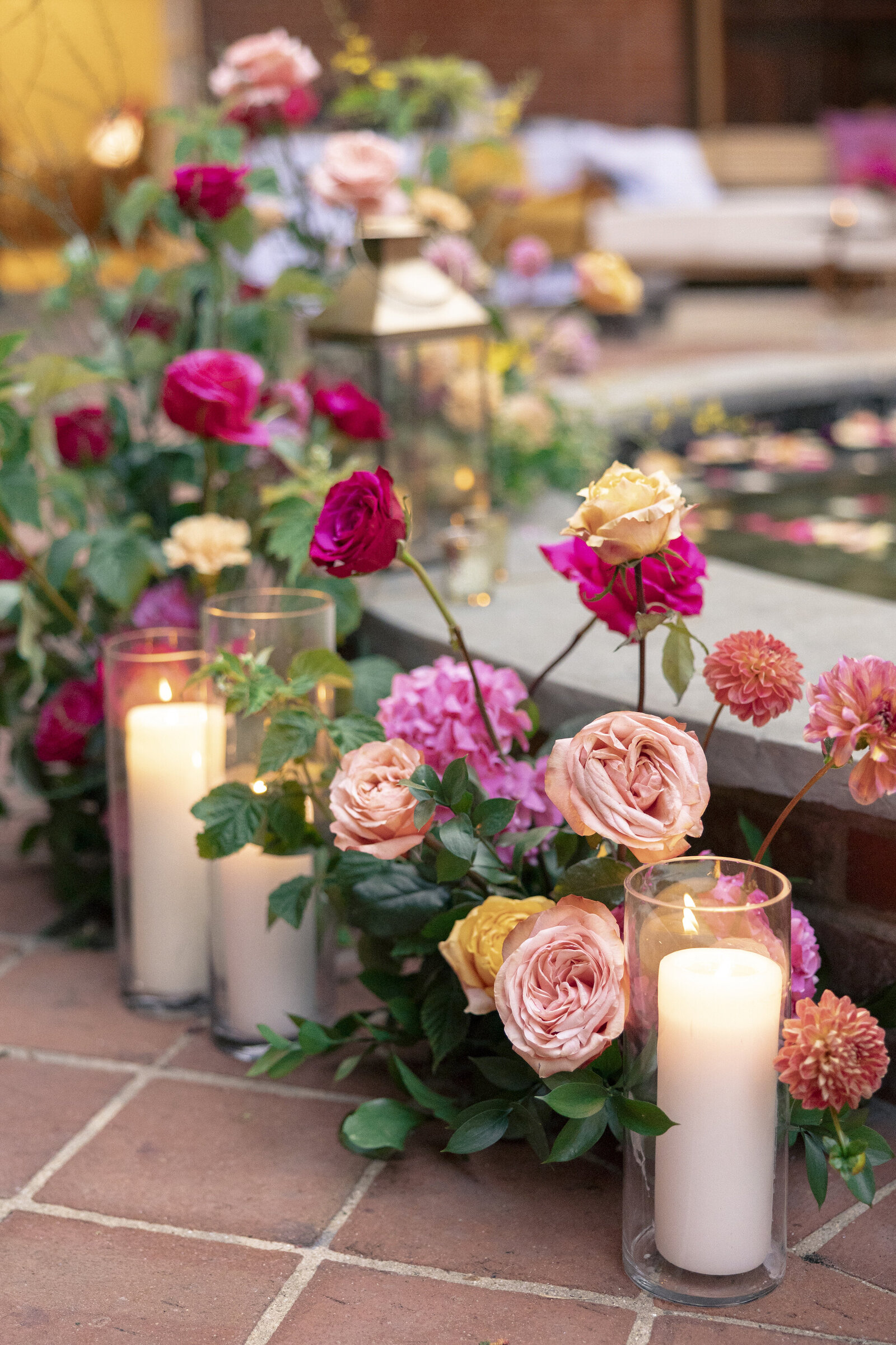 Floral ground piece around fountain at Gramercy Mansion in Baltimore, including pink rose, peach roses and yellow roses and peach dahlias with ivory candles nestled in between.