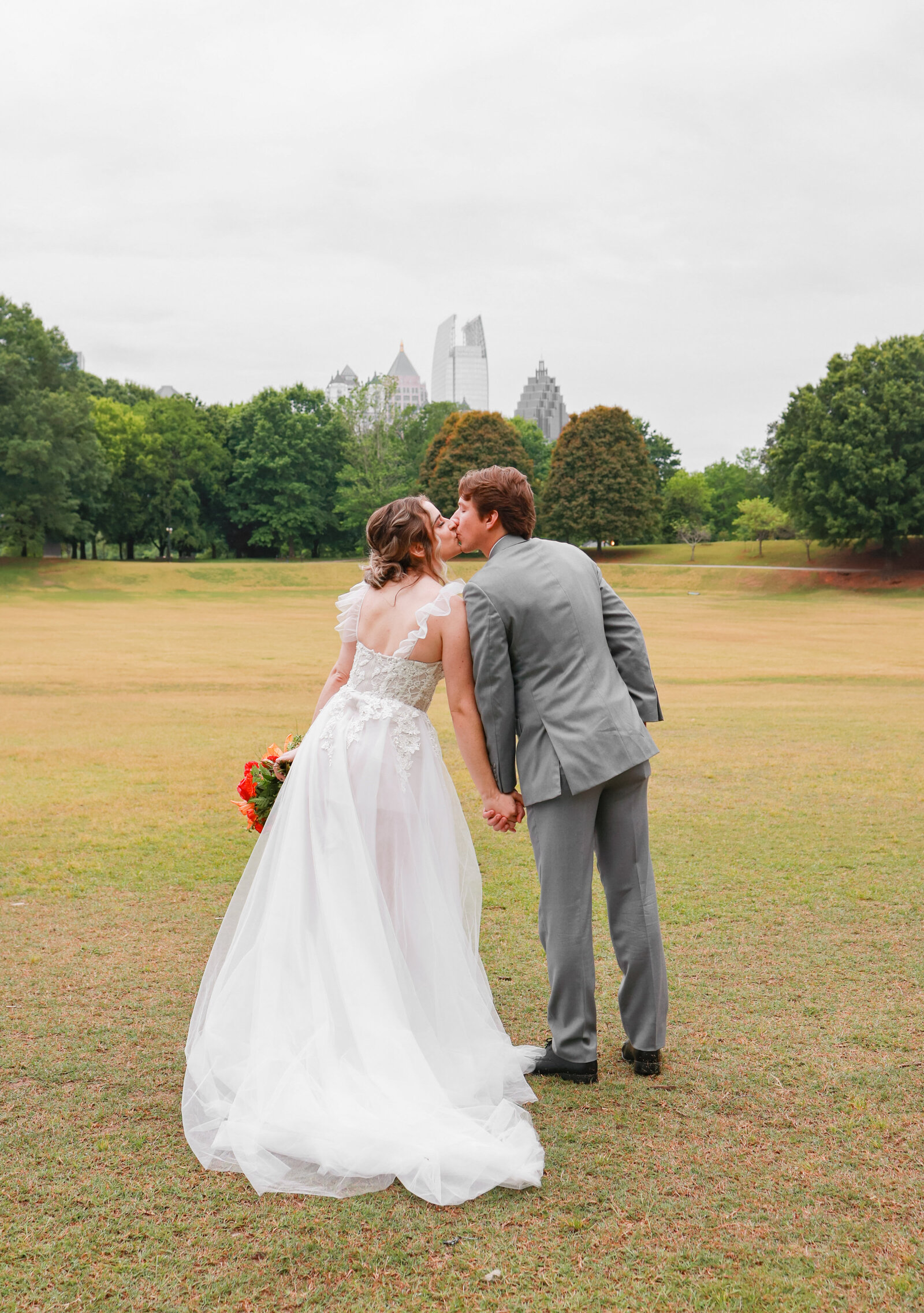 bride and groom kissing in a park with green trees in Atlanta Georgia 