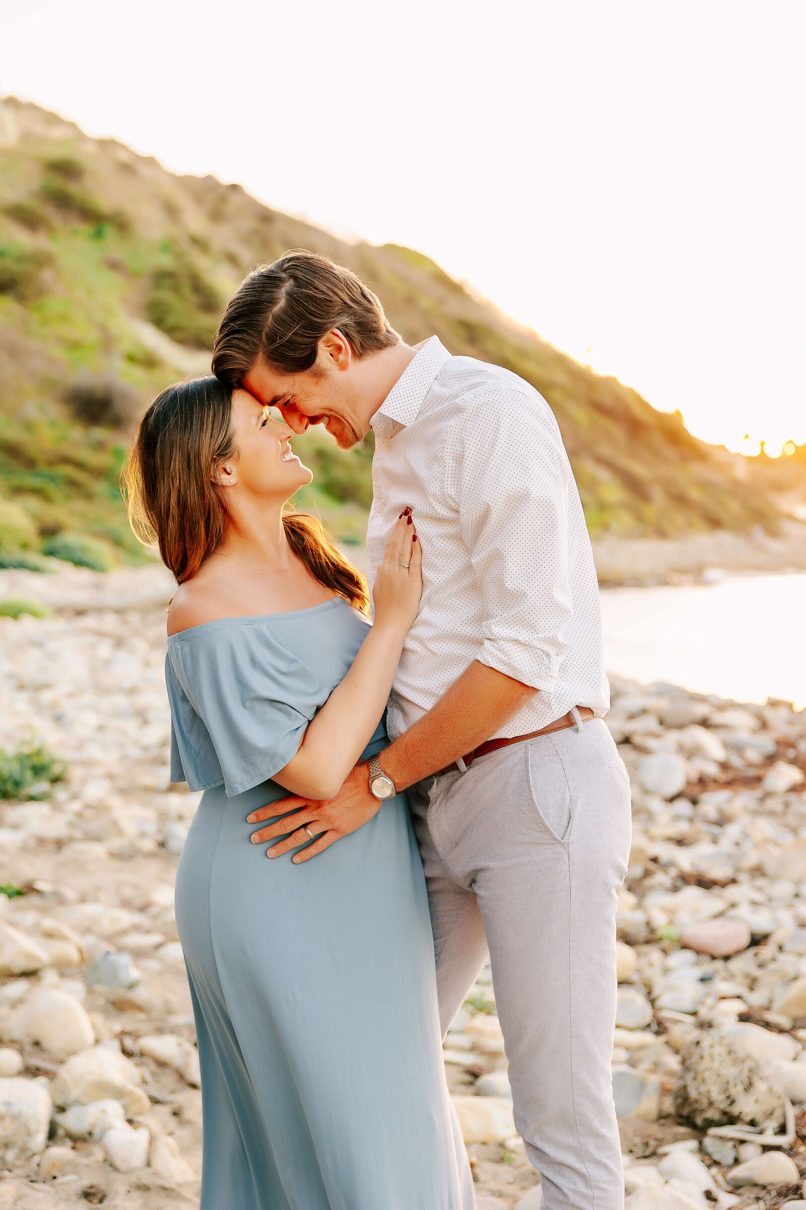 Couple embraced with foreheads touching on rocky beach in Los Angeles by Ashley Nicole Photography.