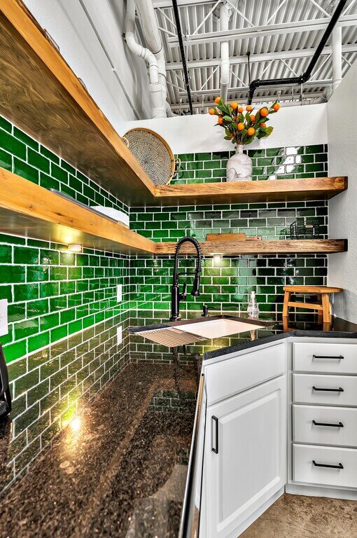 Stylish kitchen with vibrant greens and open shelving in this one-bedroom, one-bathroom vacation rental condo with sleeping space for four is walking distance from the Silos, McLane Stadium, and Baylor University in downtown Waco, TX